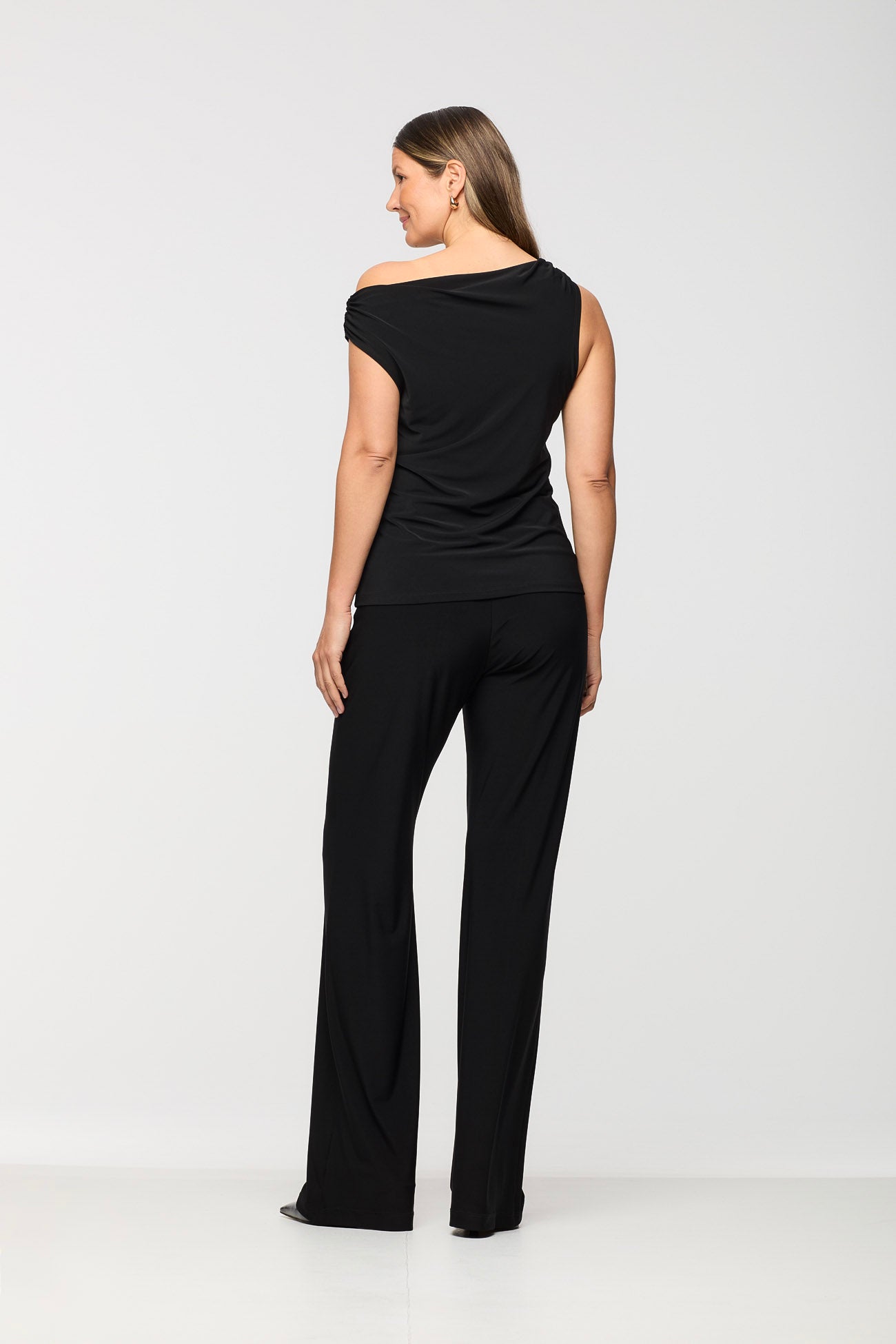 Woman wearing a black off-shoulder top and black pants on a white background