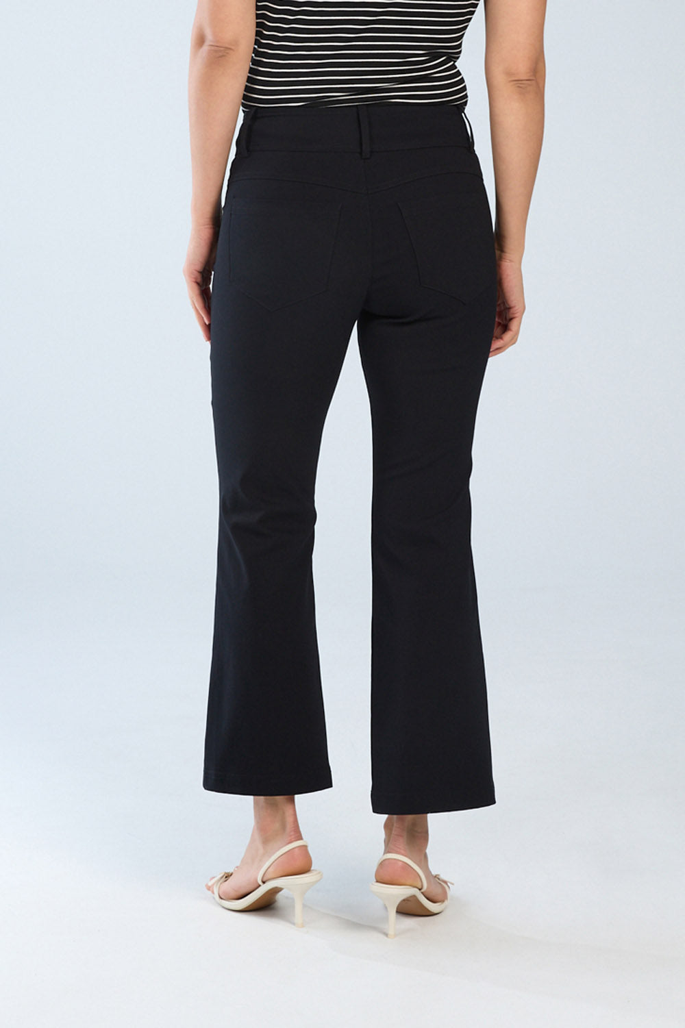 Person wearing black pants and a striped top on a white background back view