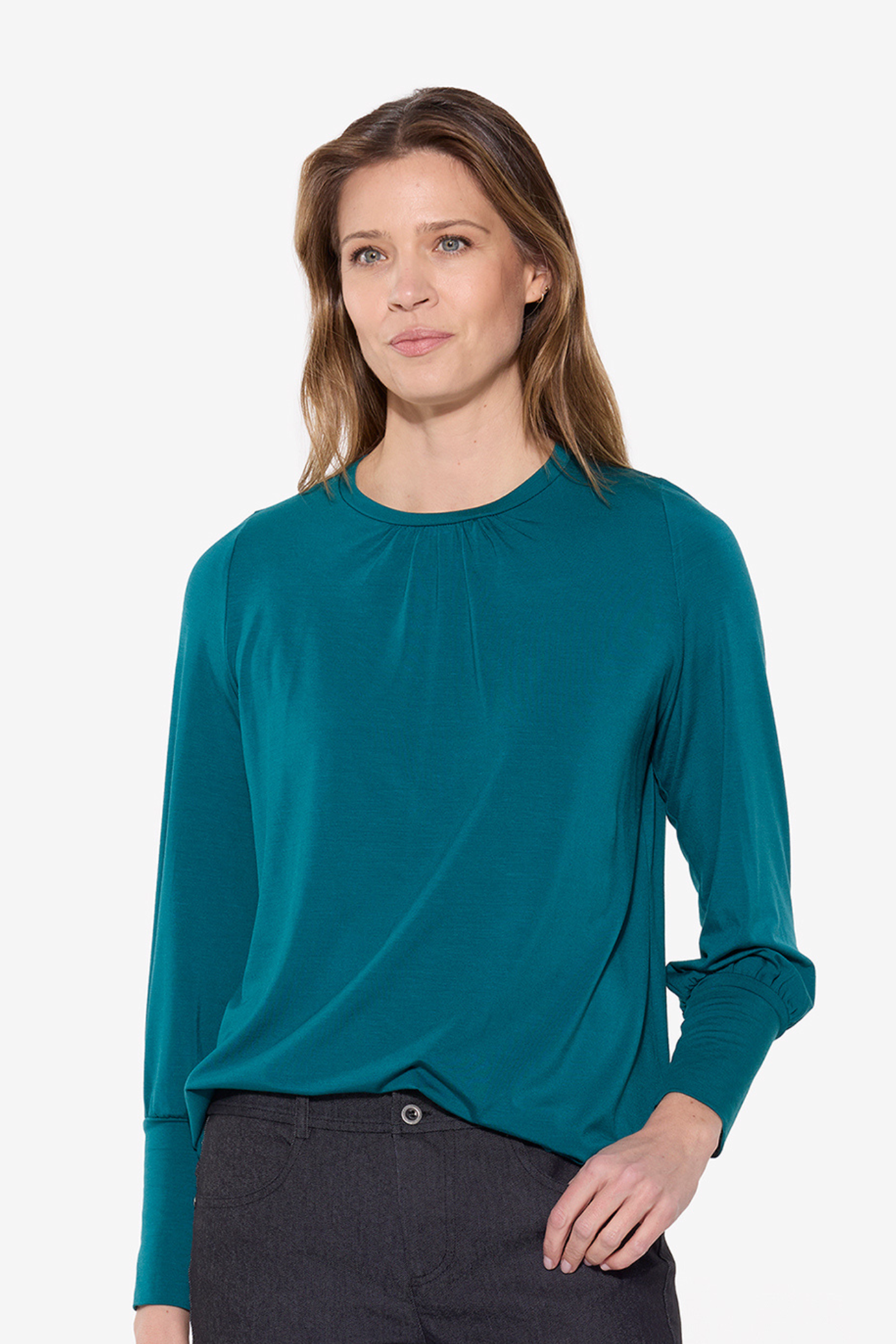 Woman wearing a teal long-sleeve top on a white background