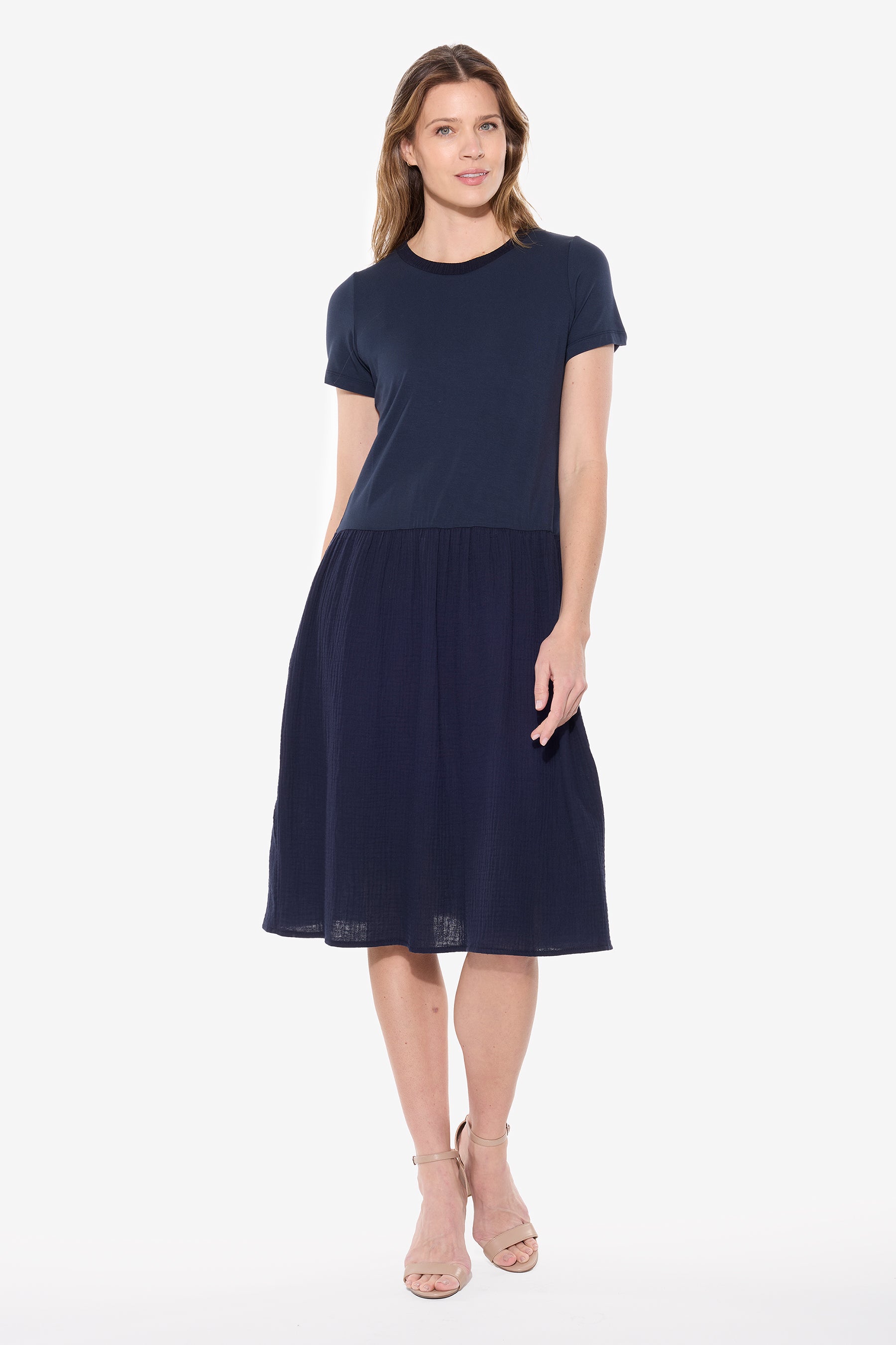 Woman wearing a navy mixed media dress with short sleeves, crew neckline, fitted top and knee-length cotton skirt with pockets