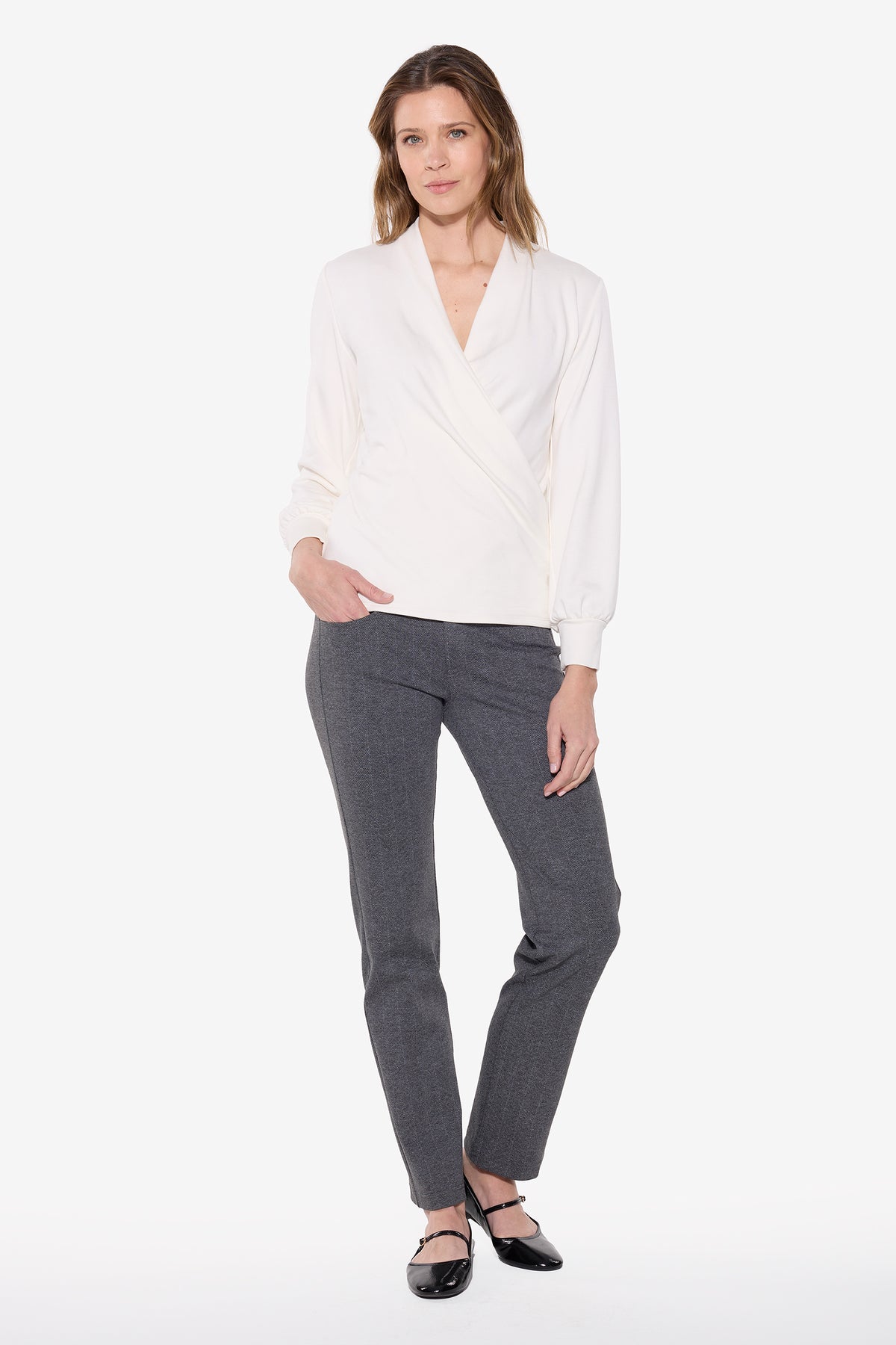 Woman wearing a white wrap top and gry chevron pants on a white background