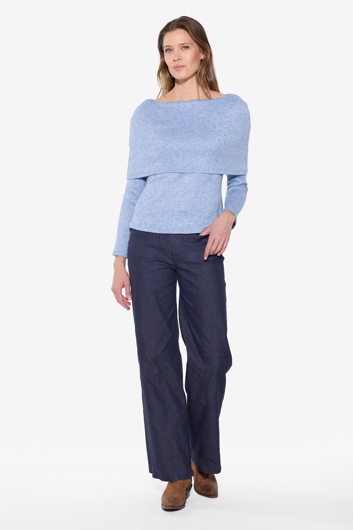 Woman wearing a light blue off-shoulder top and dark blue pants on a white background