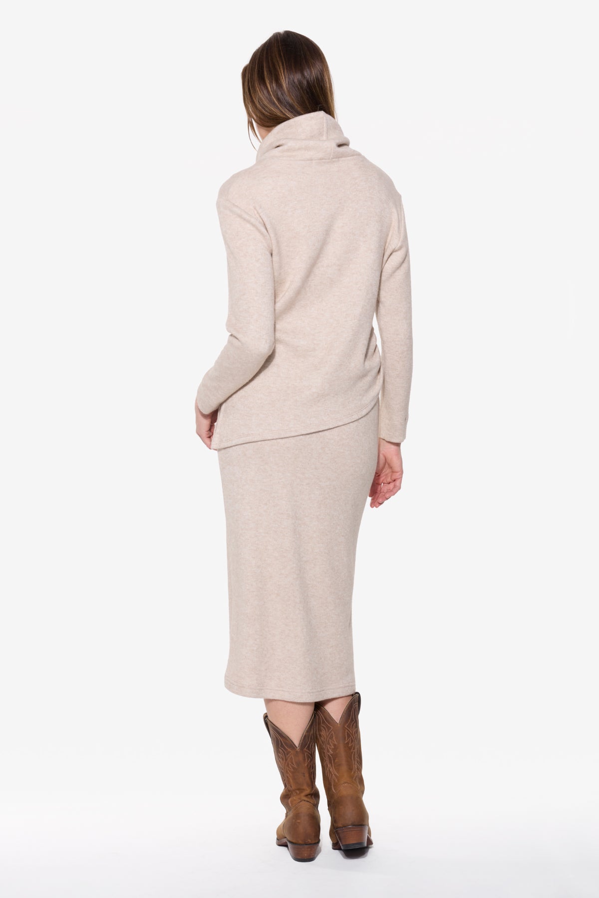 Woman wearing a beige outfit with a matching skirt and jacket on a white background