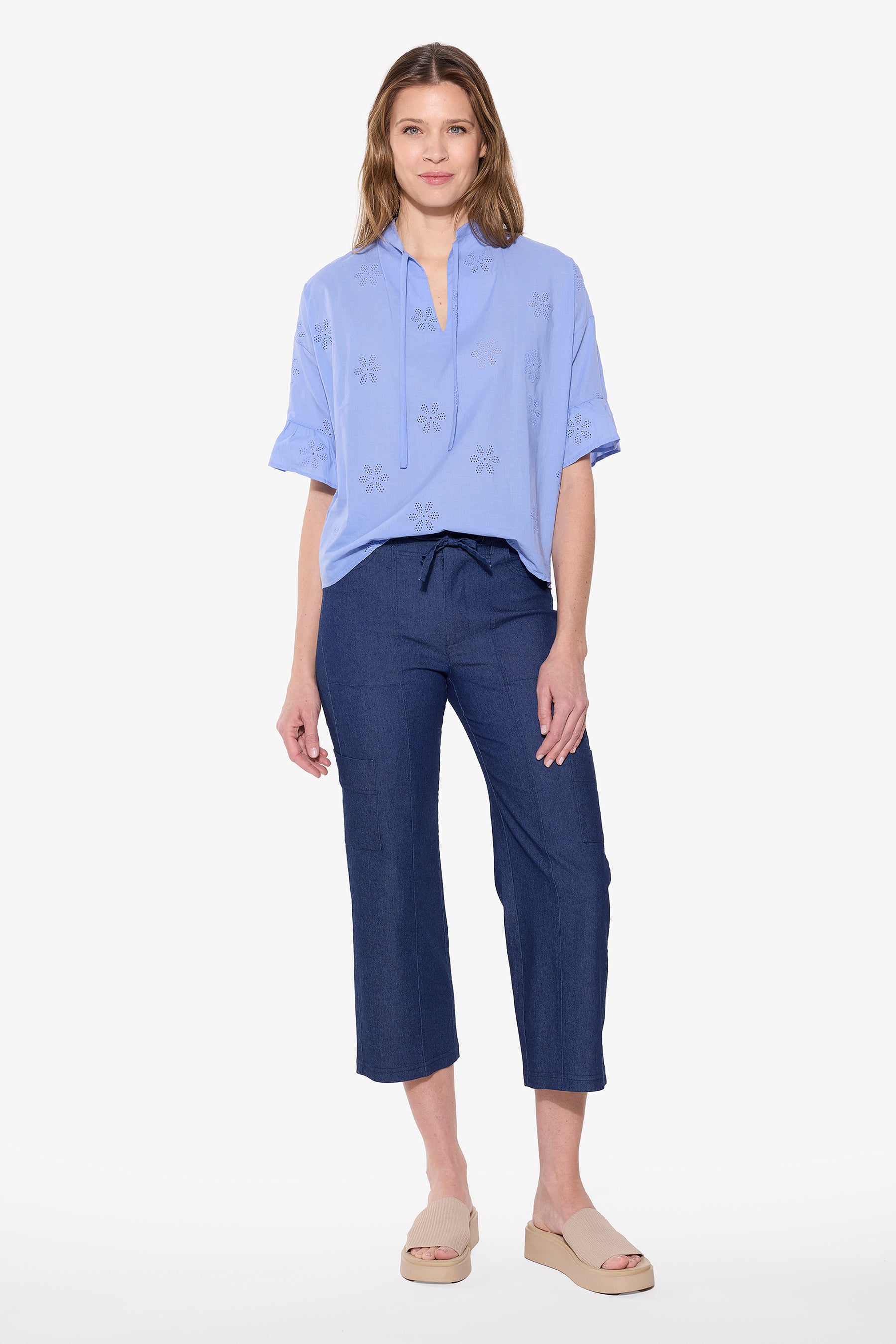 Woman wearing a light blue top and dark blue pants on a white background