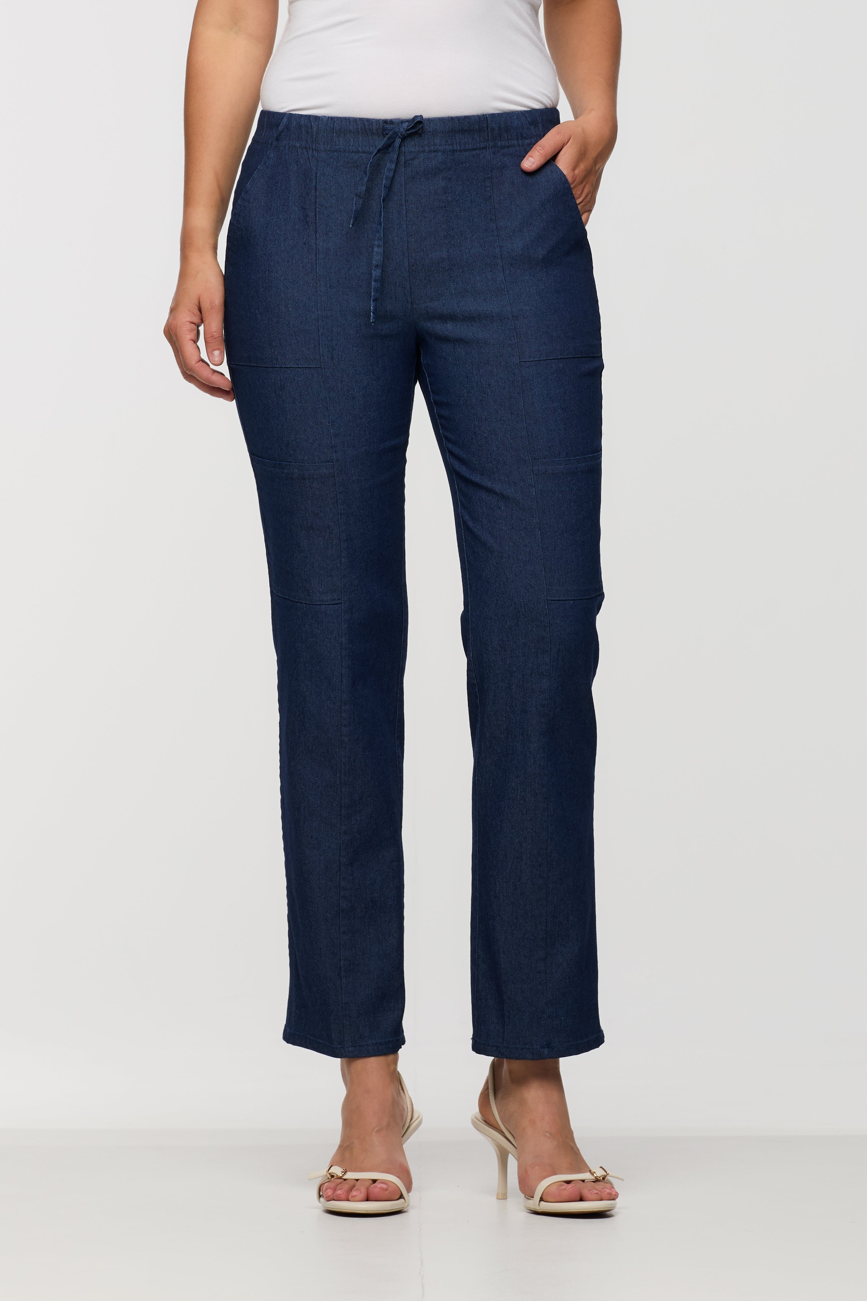 Woman wearing dark indigo drawstring straight leg pants with an elastic waistband and relaxed fit, shown from the front.