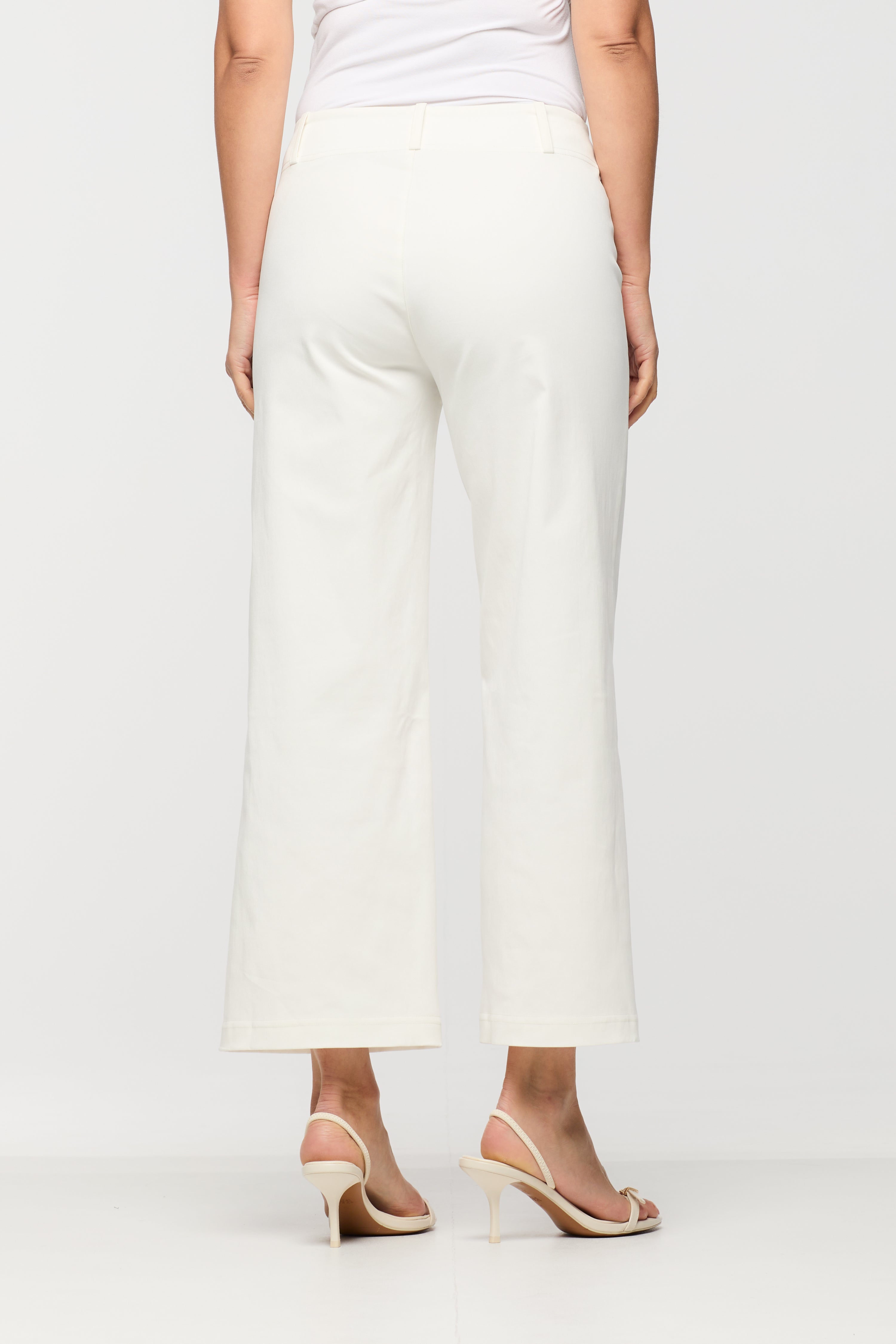 Person wearing white pants on a plain background side back view