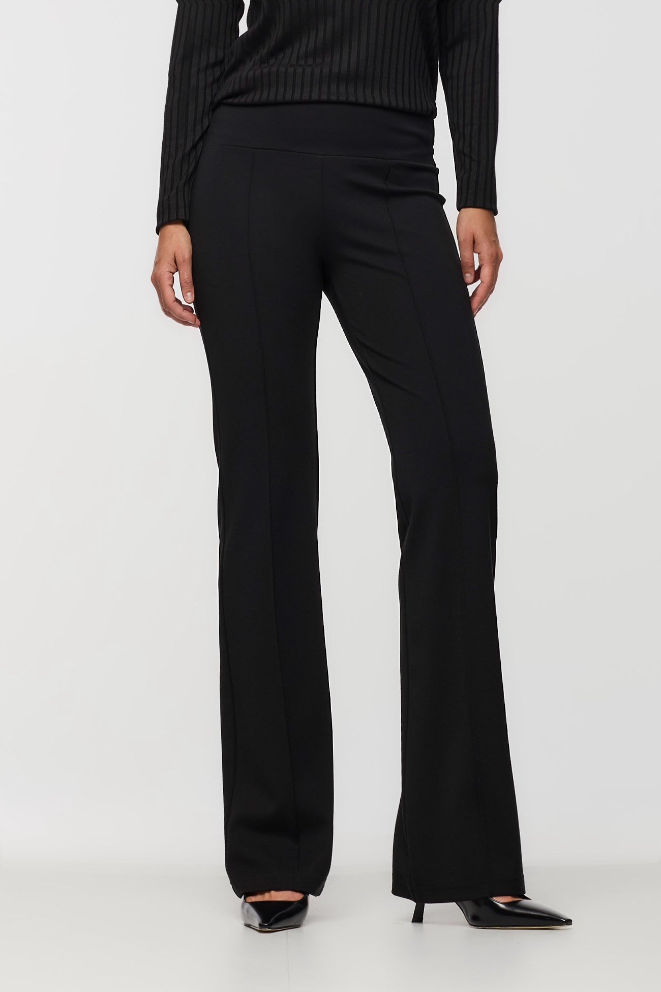 Black pants worn by a person on a white background