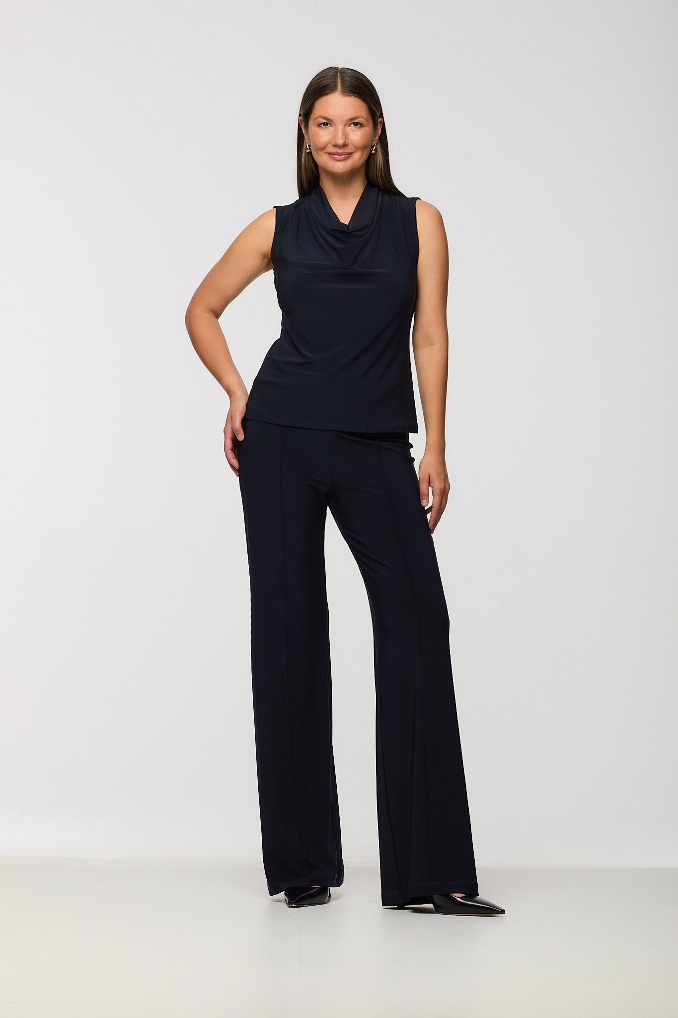 Woman wearing a navy sleeveless top and pants on a white background