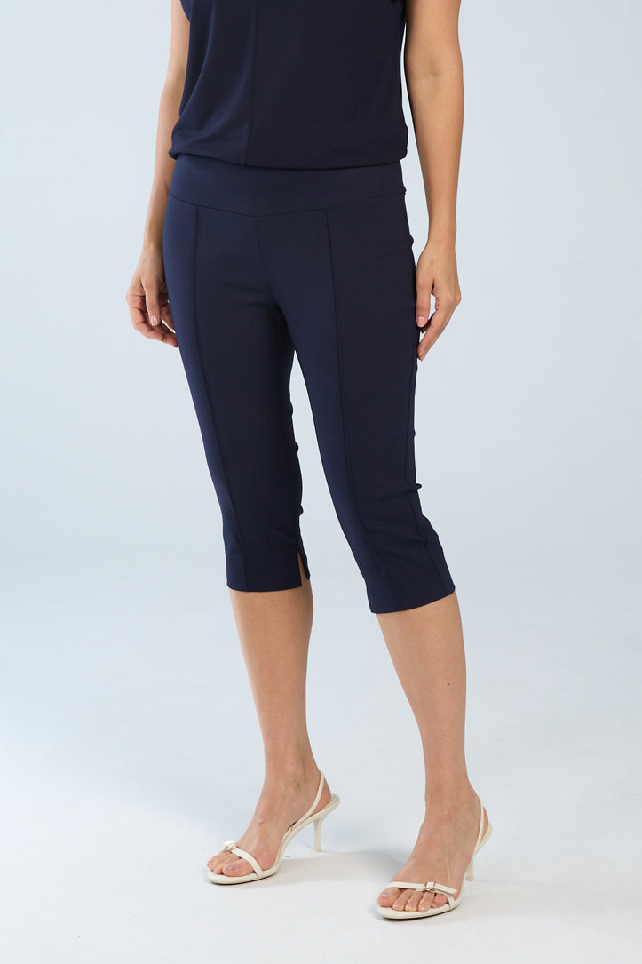 A person wearing navy pintuck capri pants with a slip-on style, standing against a plain background.