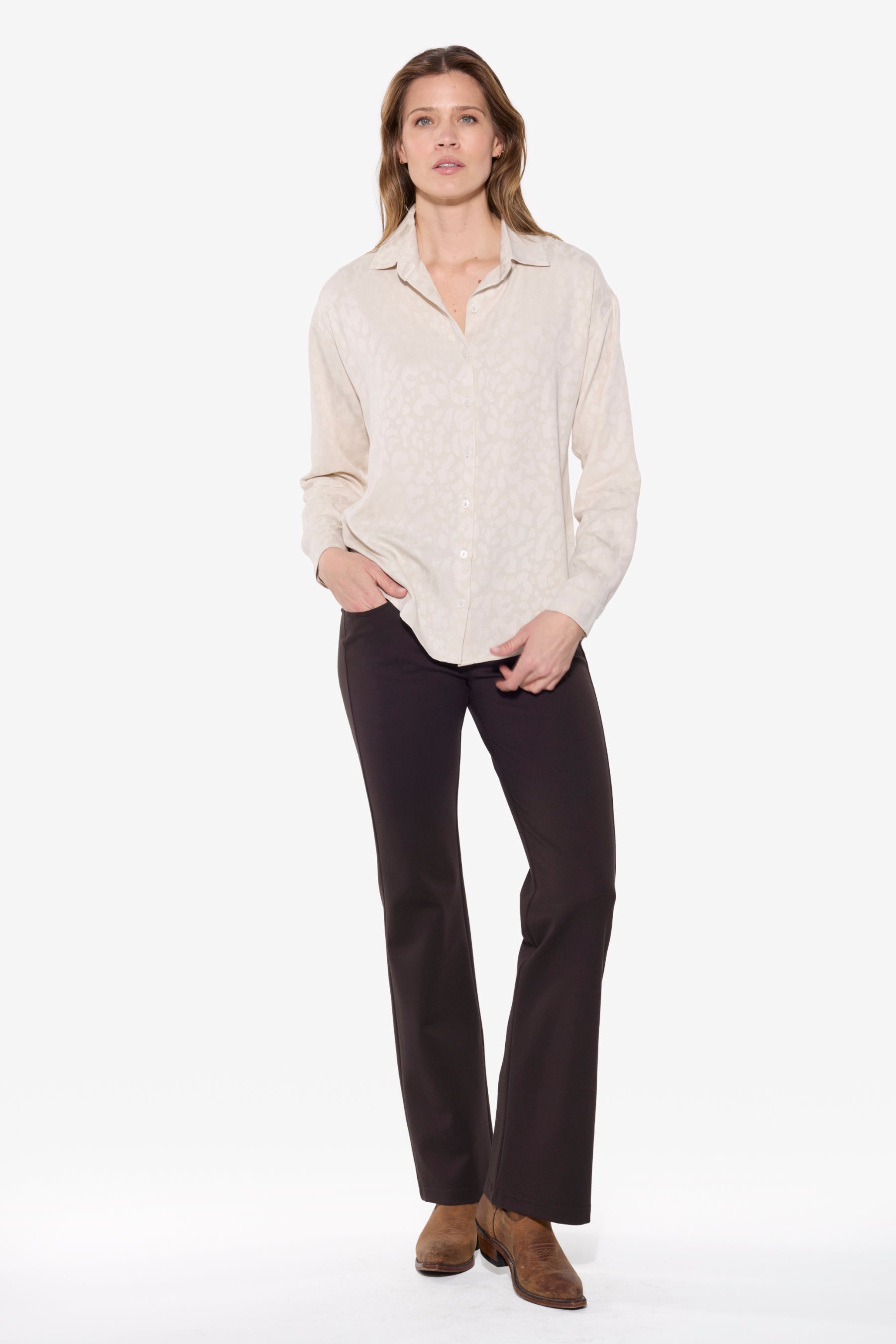 Woman wearing a light-colored blouse and dark pants on a white background