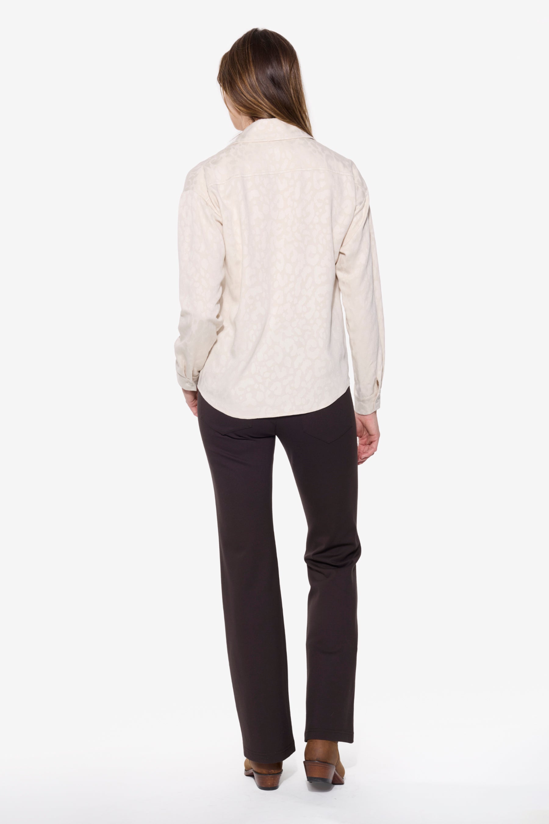 Person wearing a cream shirt and brown pants on a white background