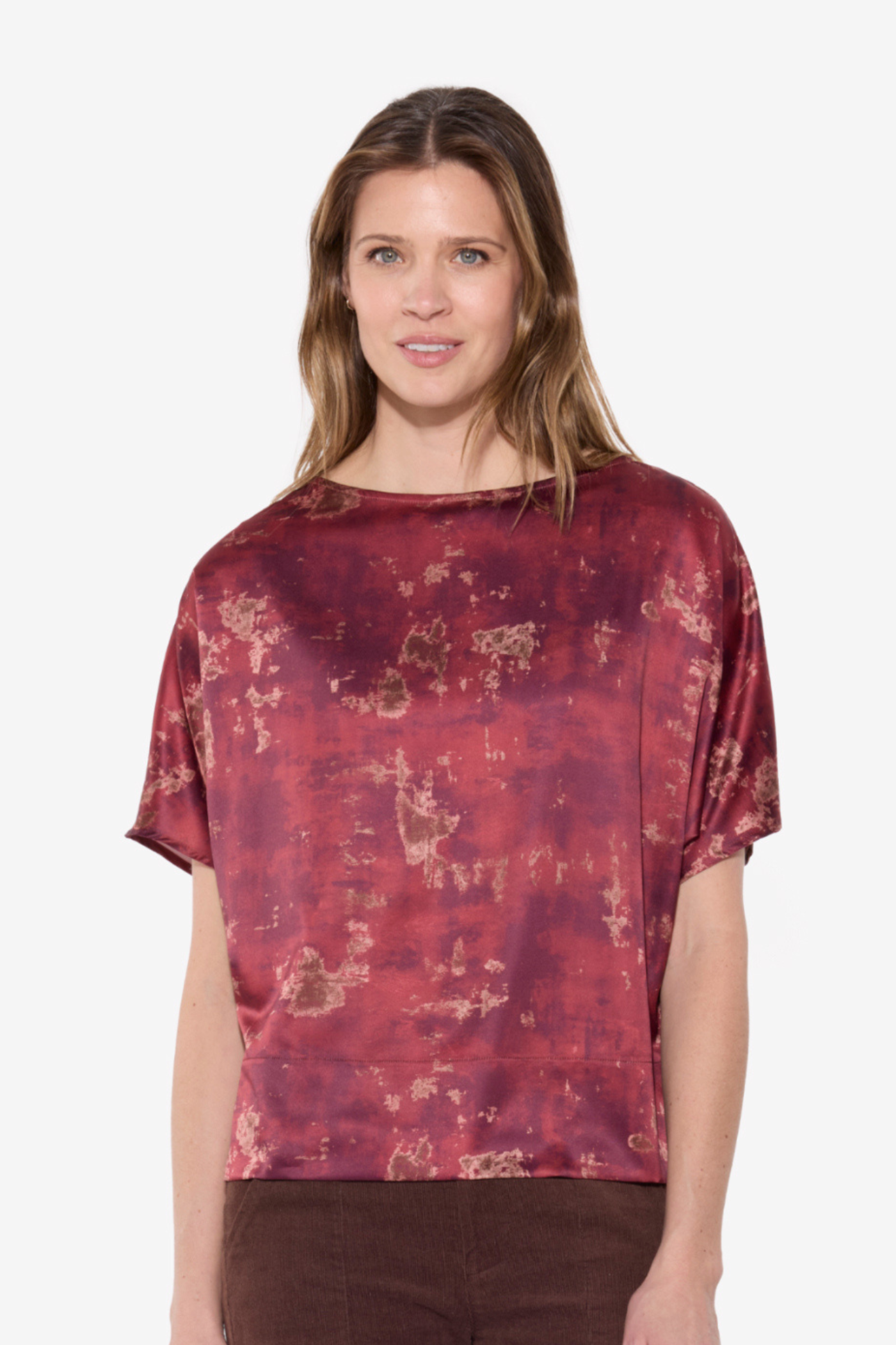 Woman wearing a maroon patterned top on a white background