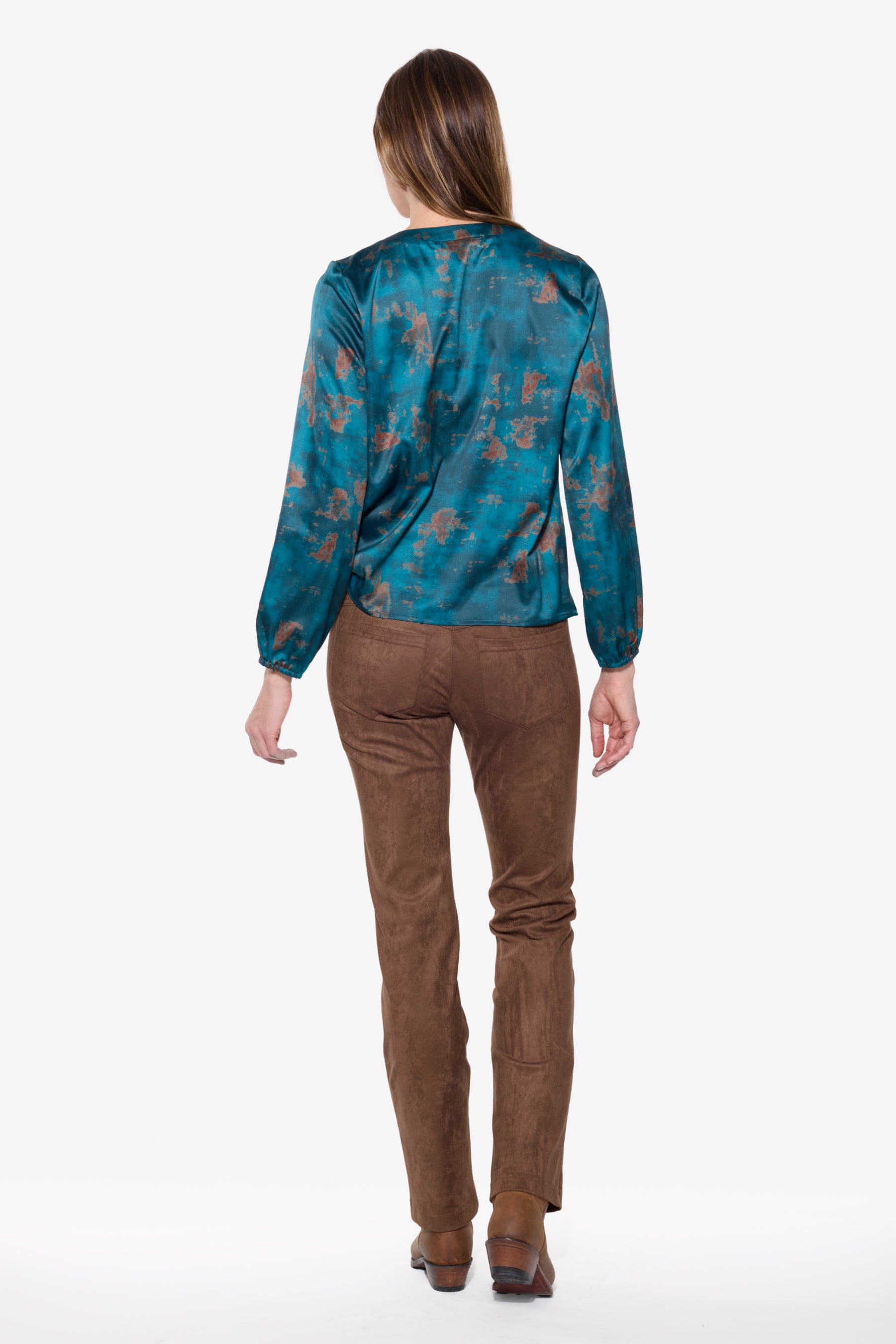 Person wearing a teal print shirt and brown pants on a white background