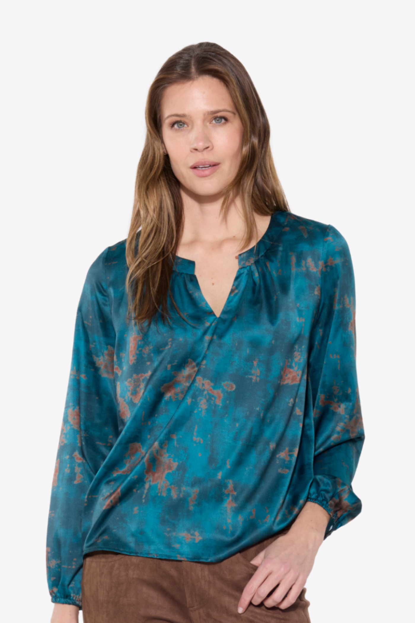 Woman wearing a teal patterned blouse against a white background