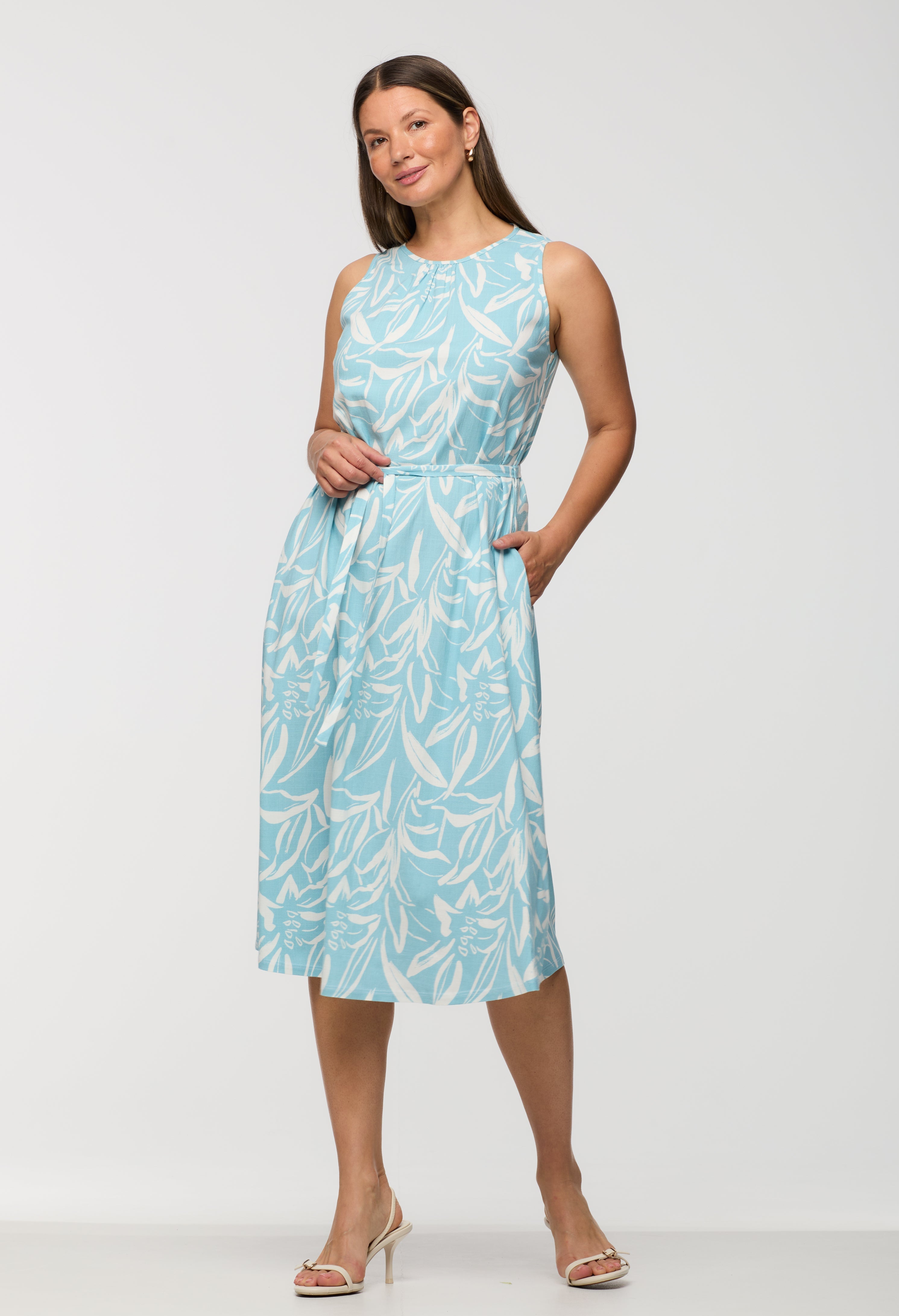 Woman wearing a light blue dress with a leaf pattern on a white background