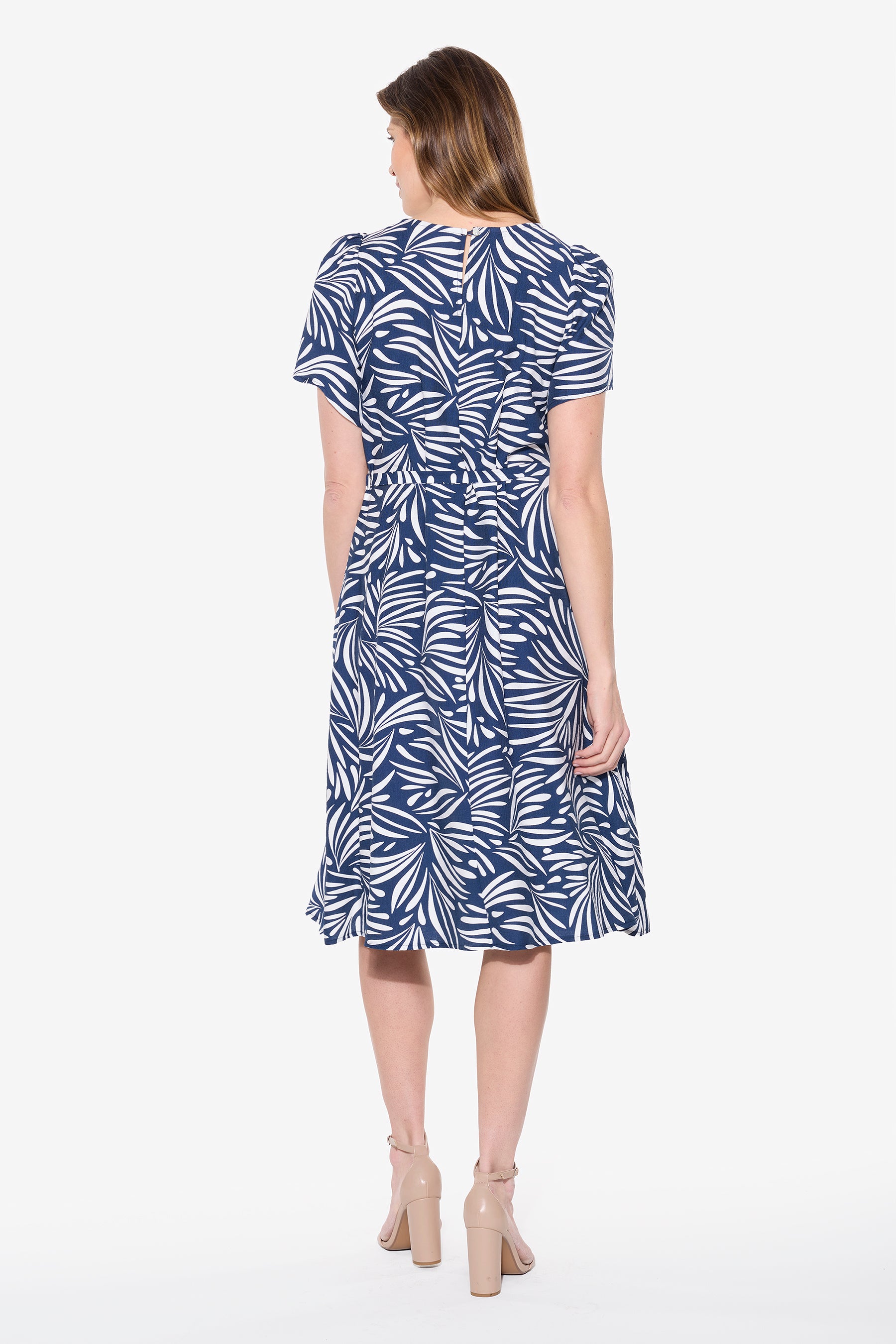 Woman wearing a blue and white patterned dress on a white background back view