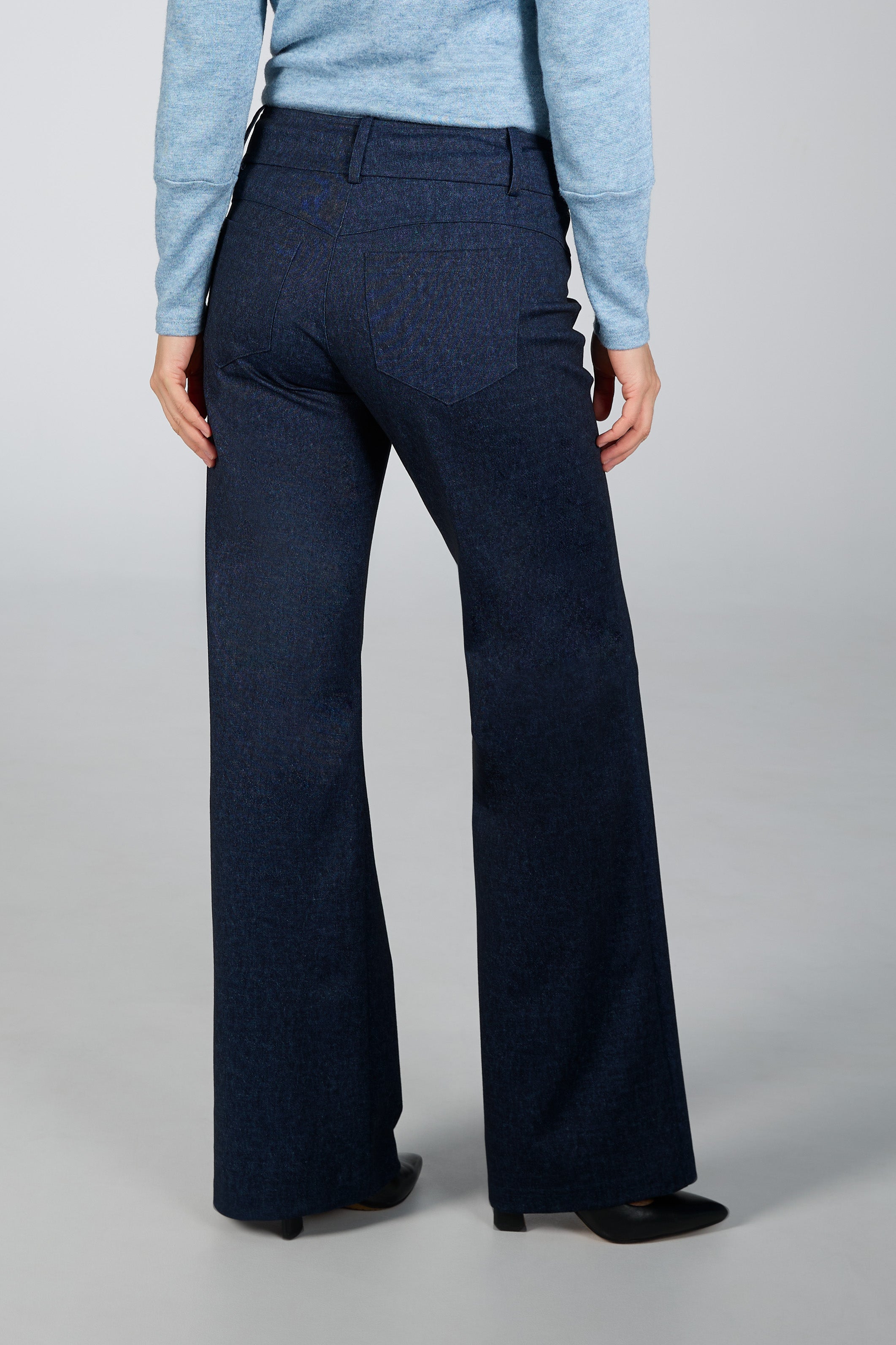 Person wearing blue sweater and dark blue wide-leg pants on a gray background