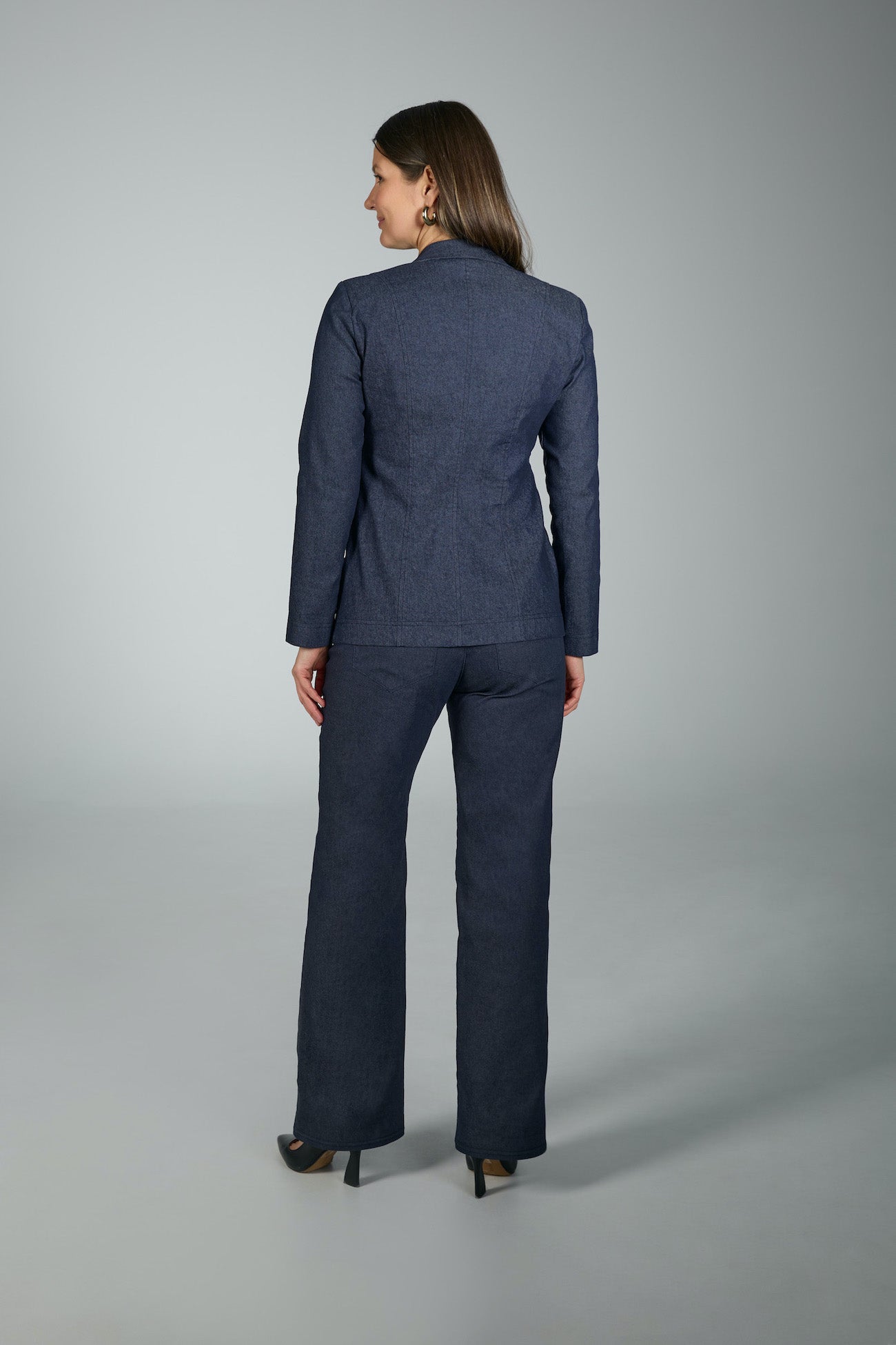 Woman wearing a navy blue suit standing against a gray background