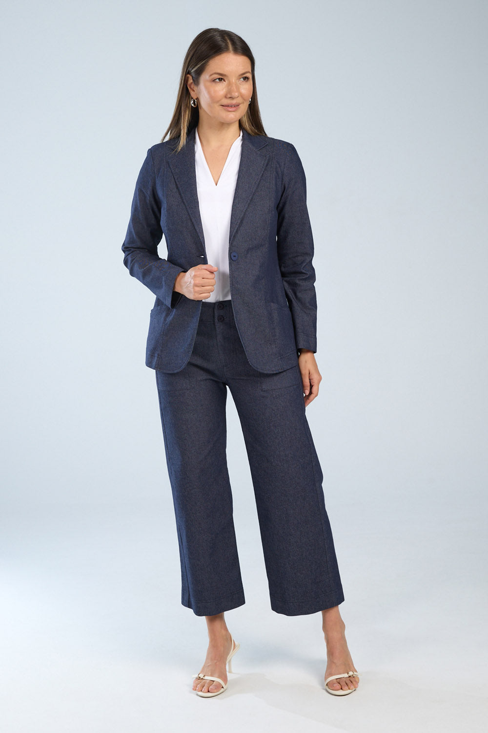 Woman wearing a navy suit with a white shirt on a light gray background