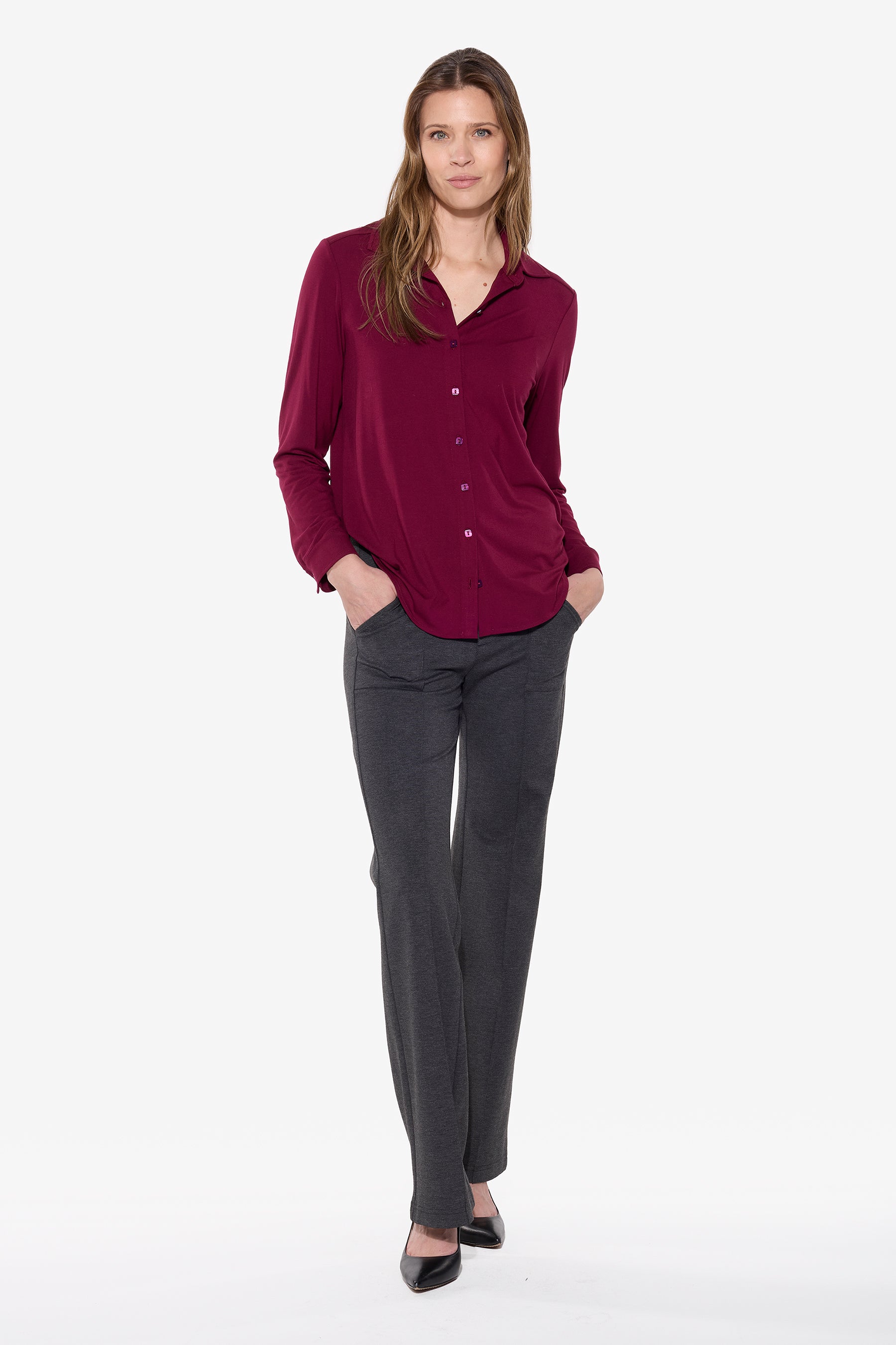 Woman wearing a maroon shirt and gray pants on a white background