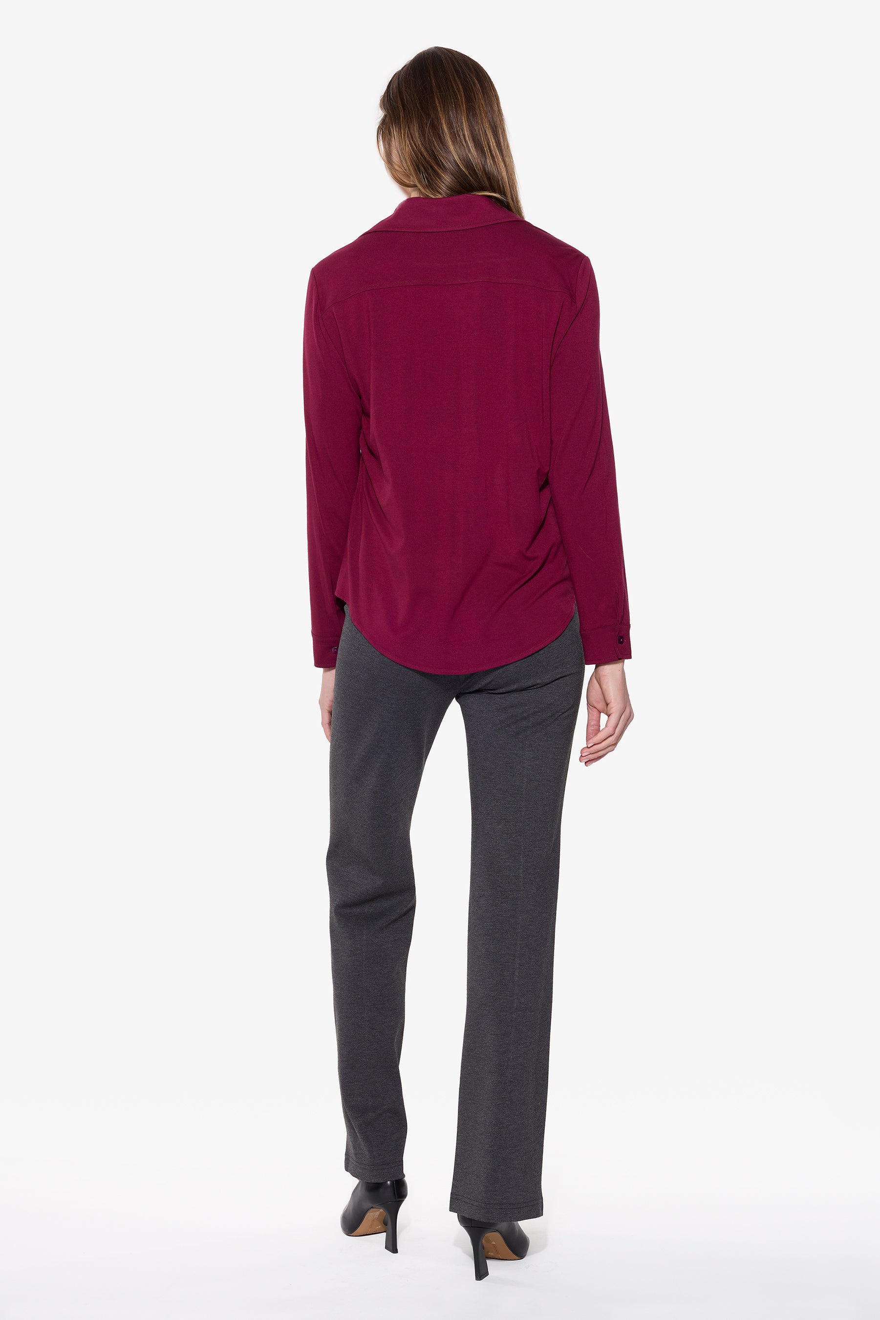 Person wearing a burgundy shirt and gray pants on a white background