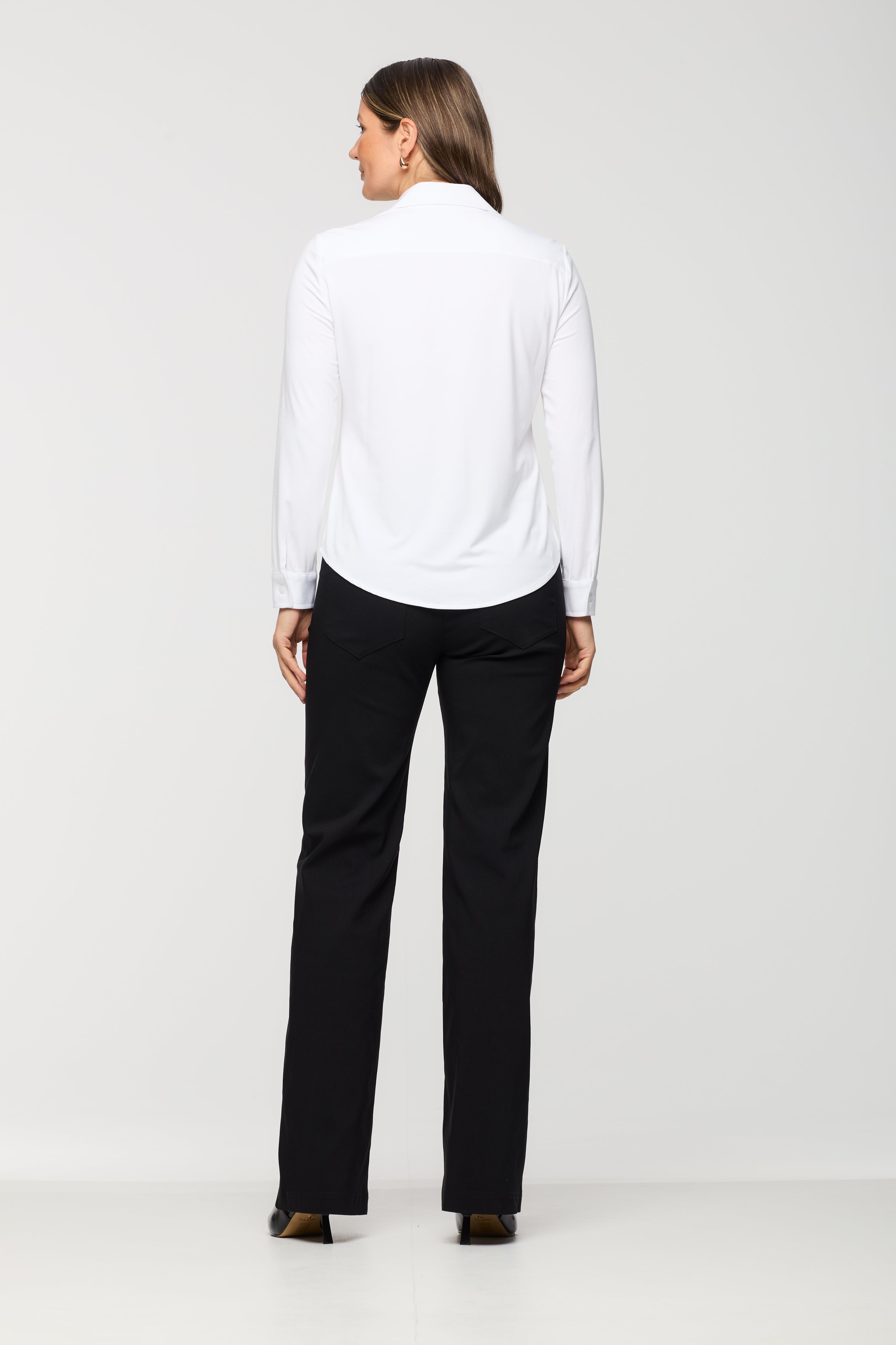 Person wearing a white shirt and black pants on a white background back view