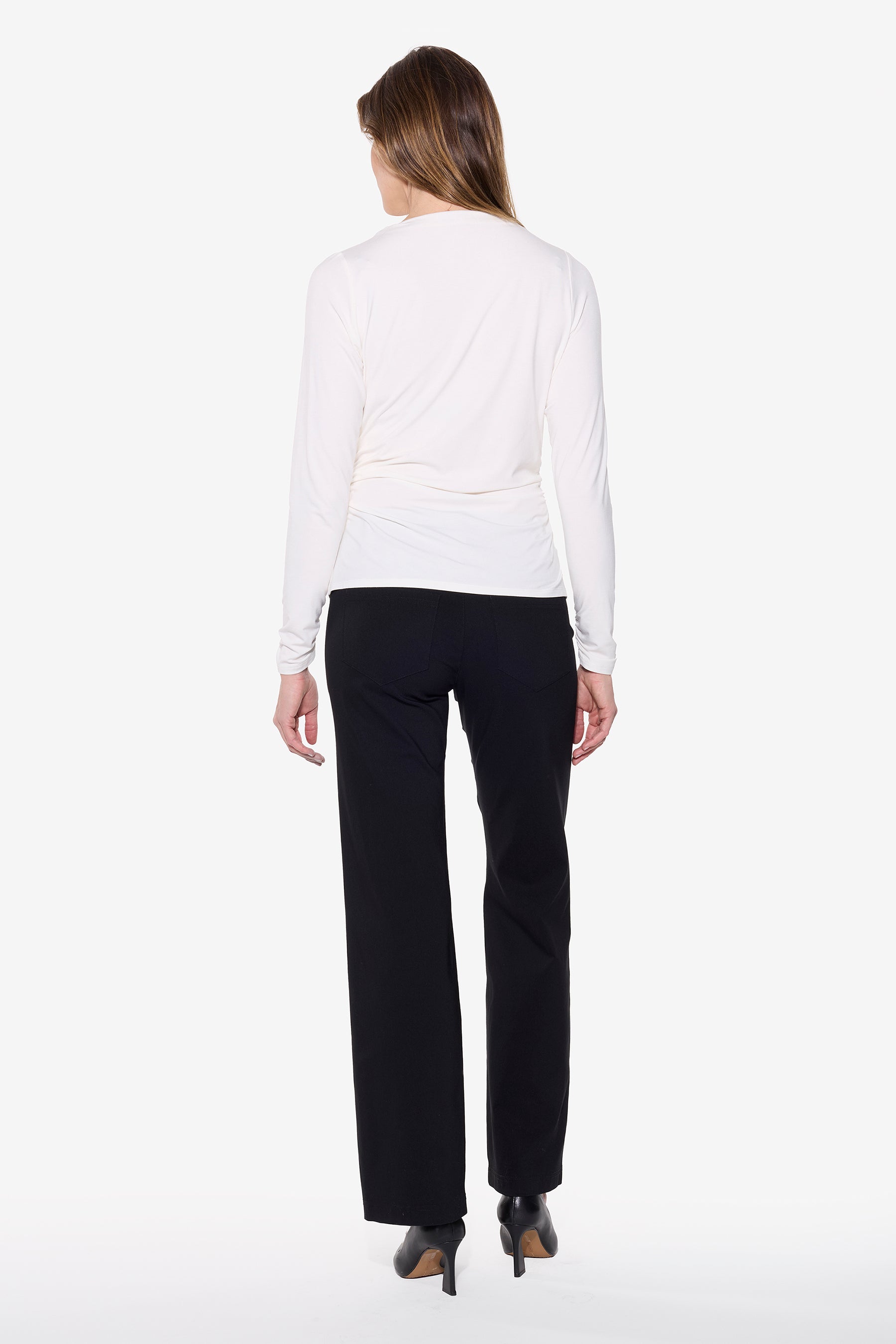Back of women wearing winter white long sleeve top with black pant and black heels