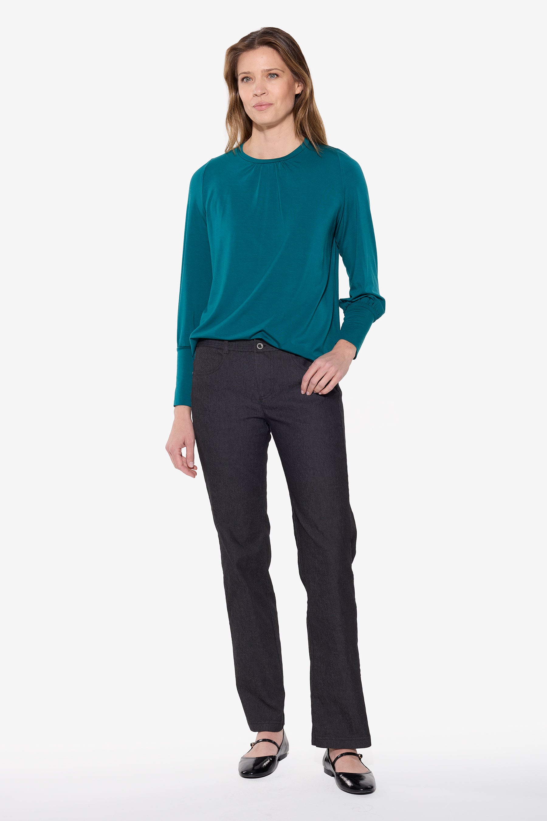Woman wearing a teal long-sleeve top and black pants on a white background