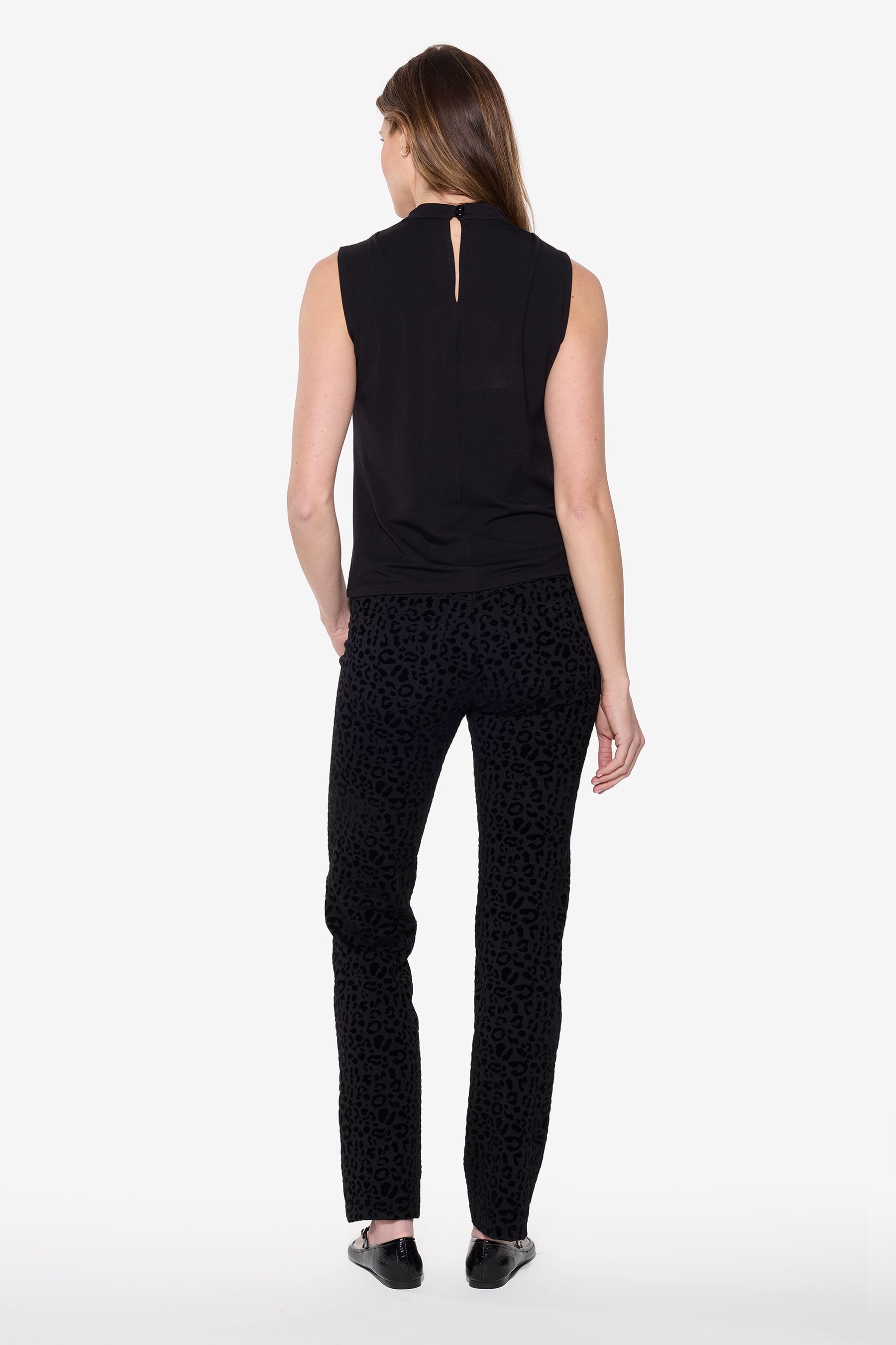 Woman wearing a black sleeveless top and patterned pants on a white background
