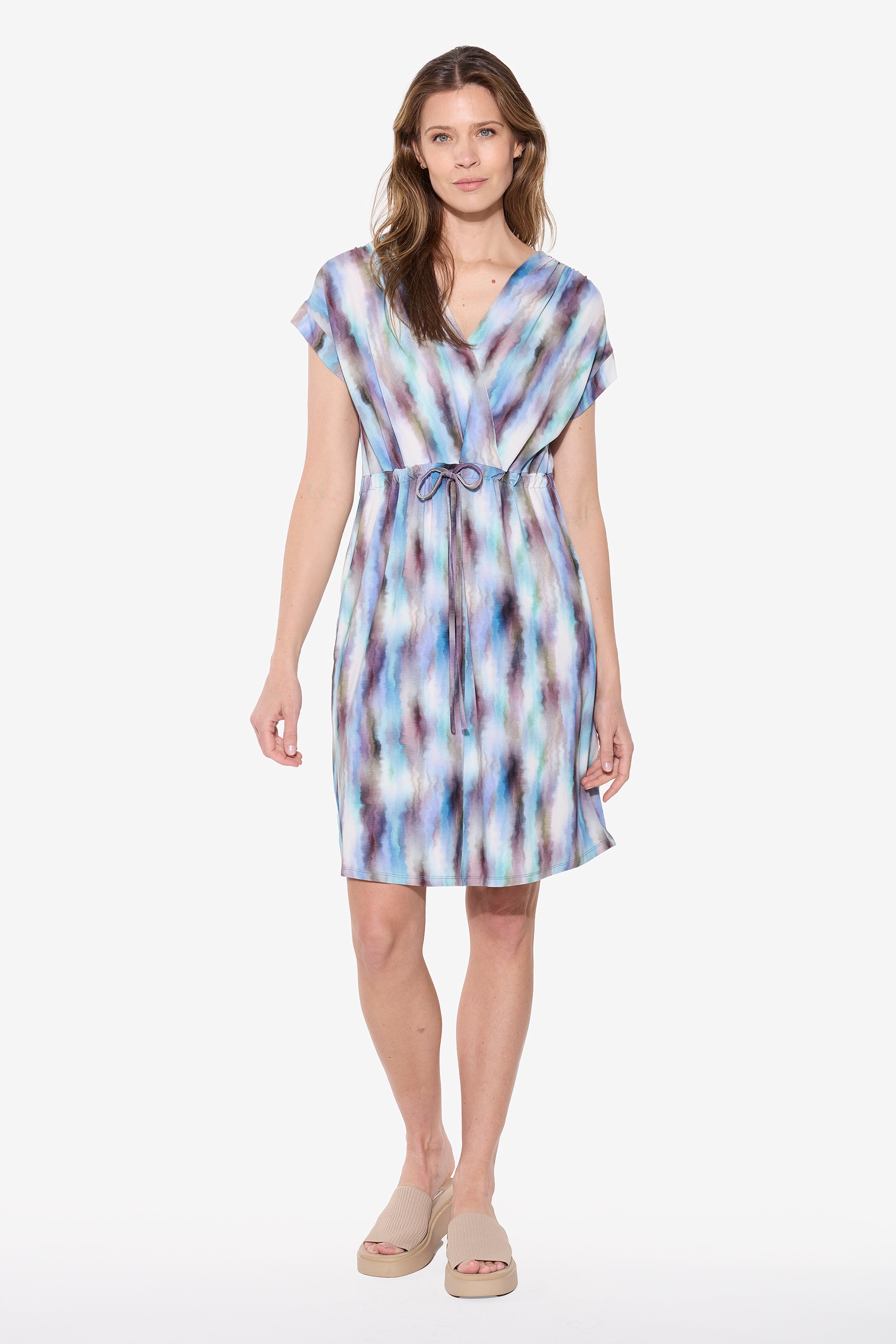 Woman wearing a blue and purple abstract print bamboo dress with short sleeves, V neckline, drawstring waist, and knee-length relaxed fit