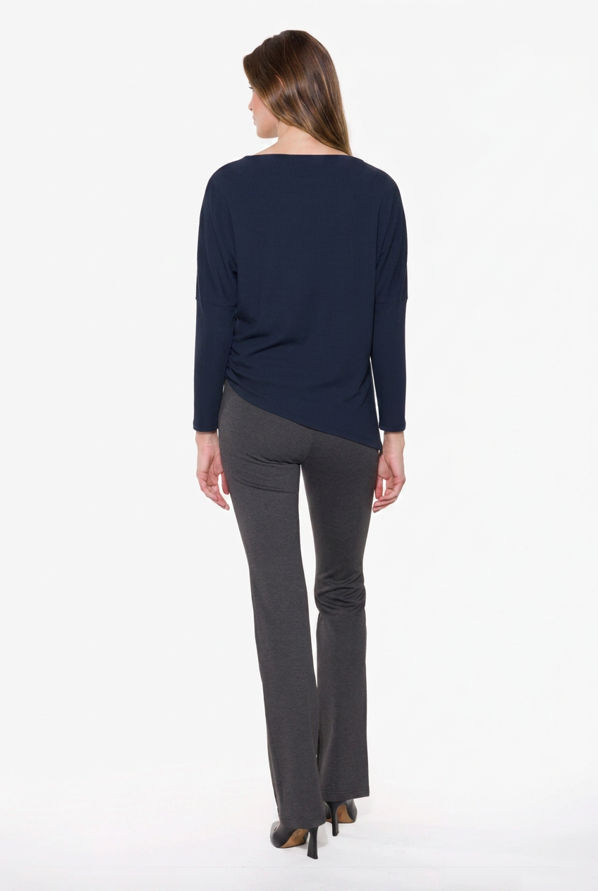 A woman viewed from the back wearing a navy blue long-sleeve top and dark gray flared pants against a plain white studio background.