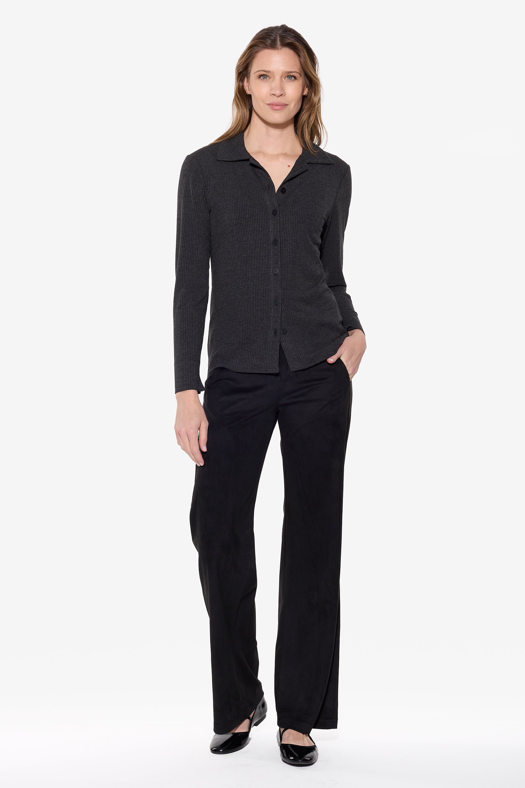 Woman wearing a charcoal shirt with black suede pants on a white background