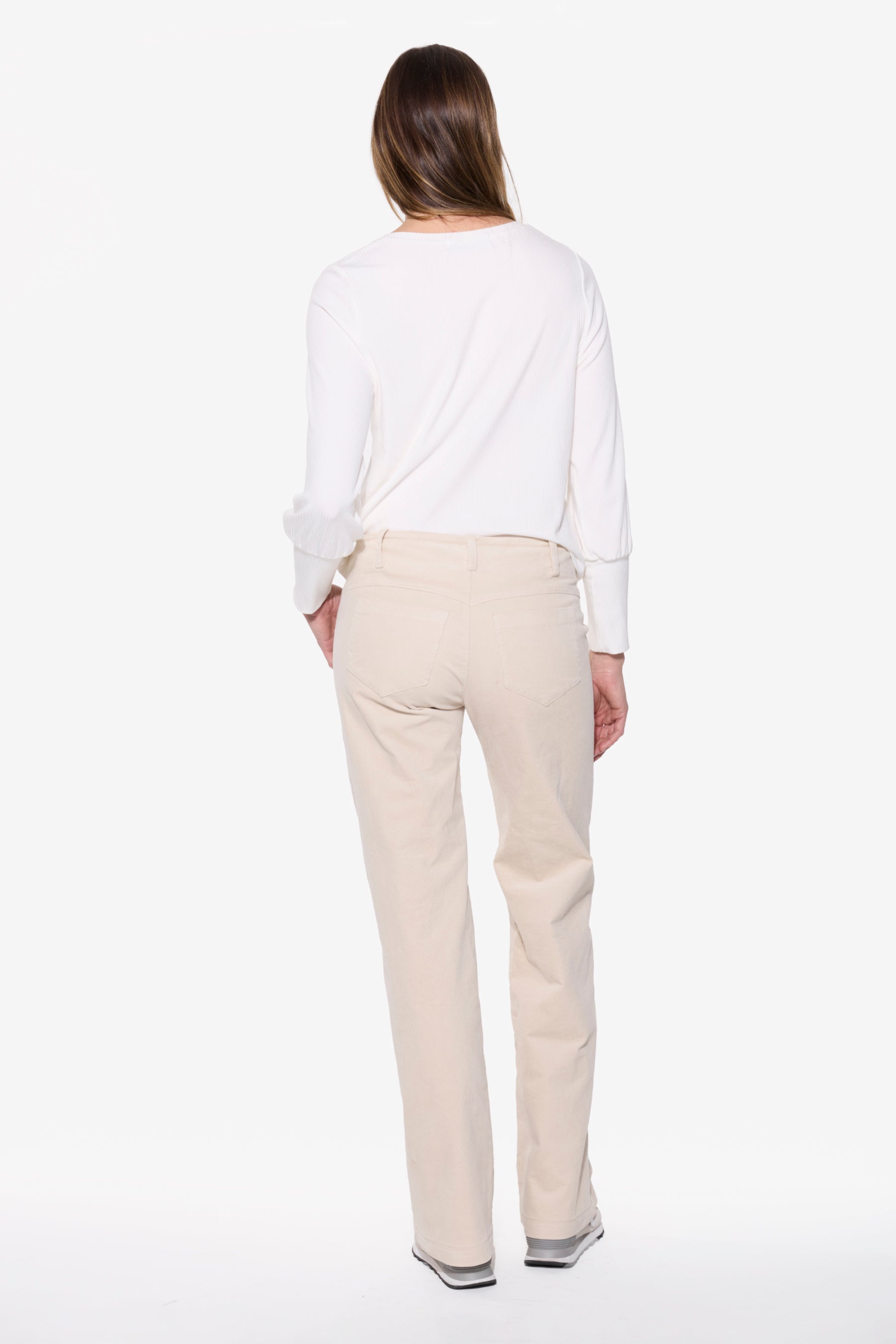 Person wearing a white top and beige pants on a white background
