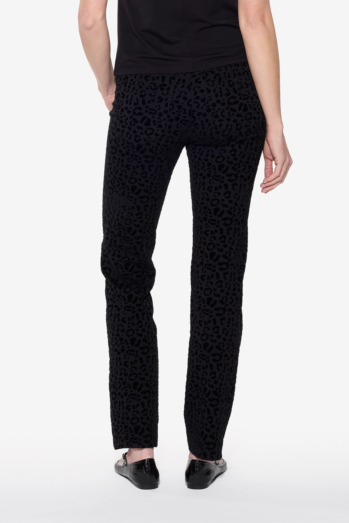 Black patterned pants worn by a person on a white background