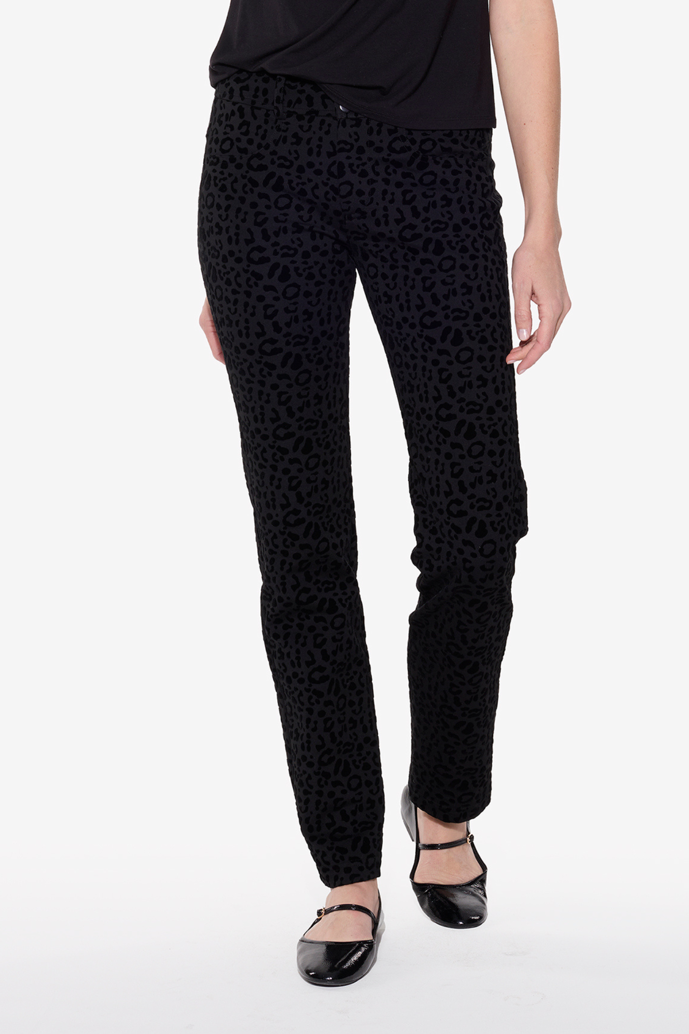 Black patterned pants worn by a person on a white background