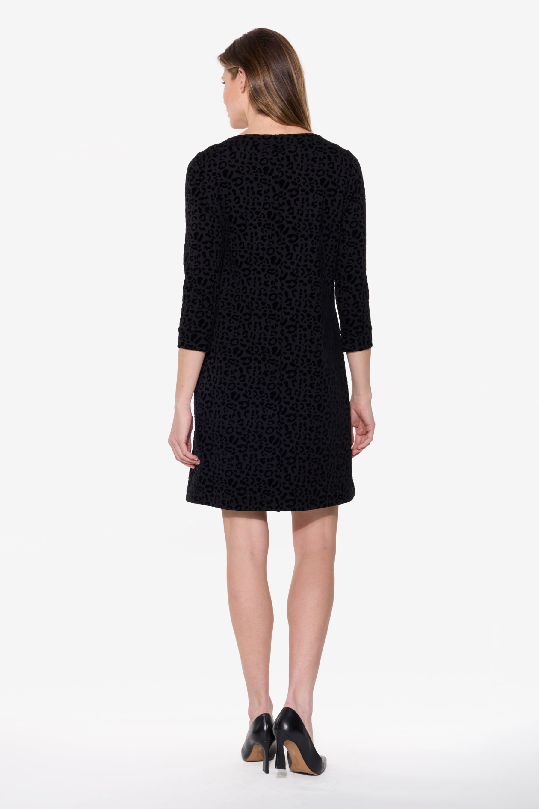 Woman wearing a black dress with a subtle pattern on a white background