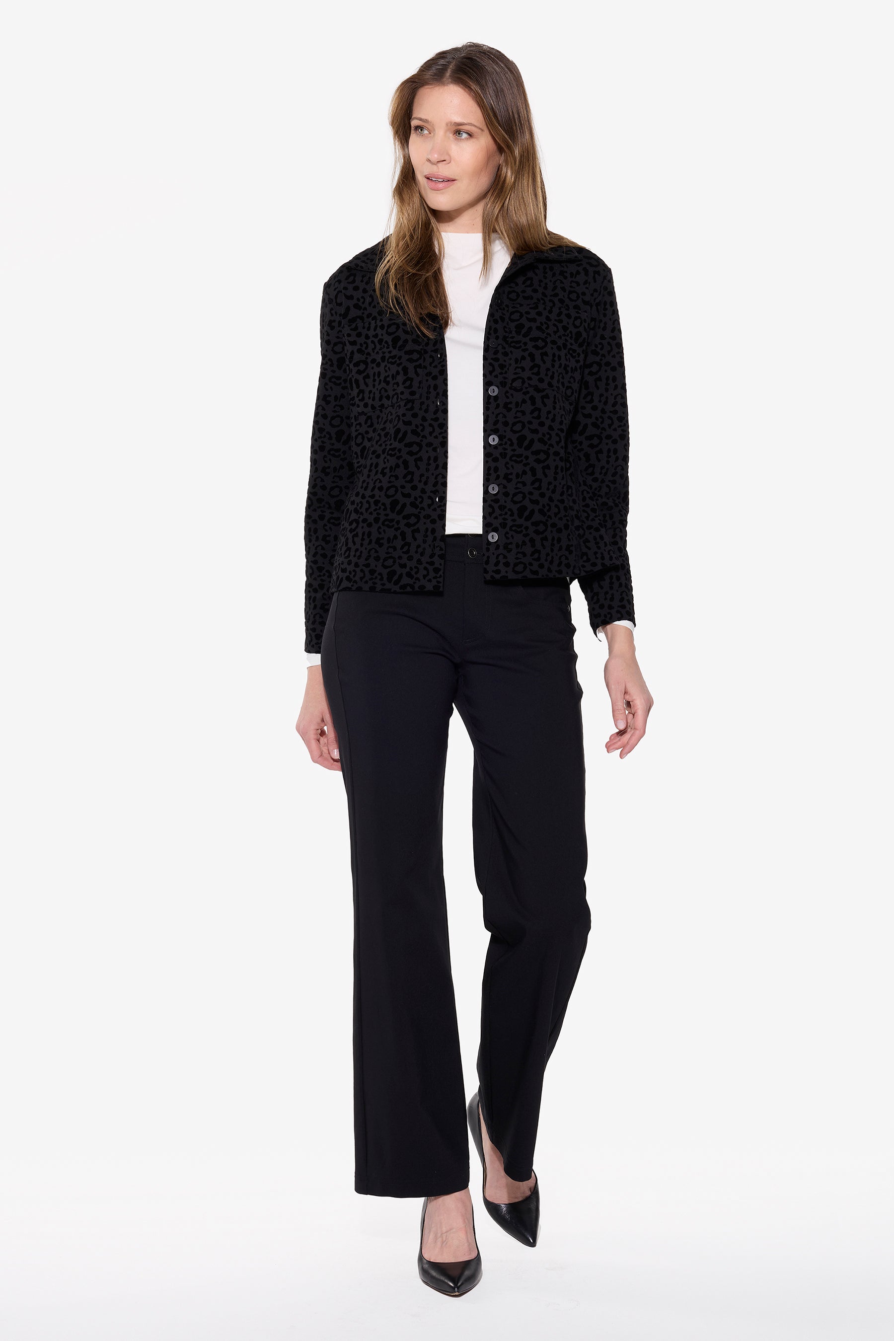 Woman wearing a black textured jacket, white shirt, and black pants on a white background