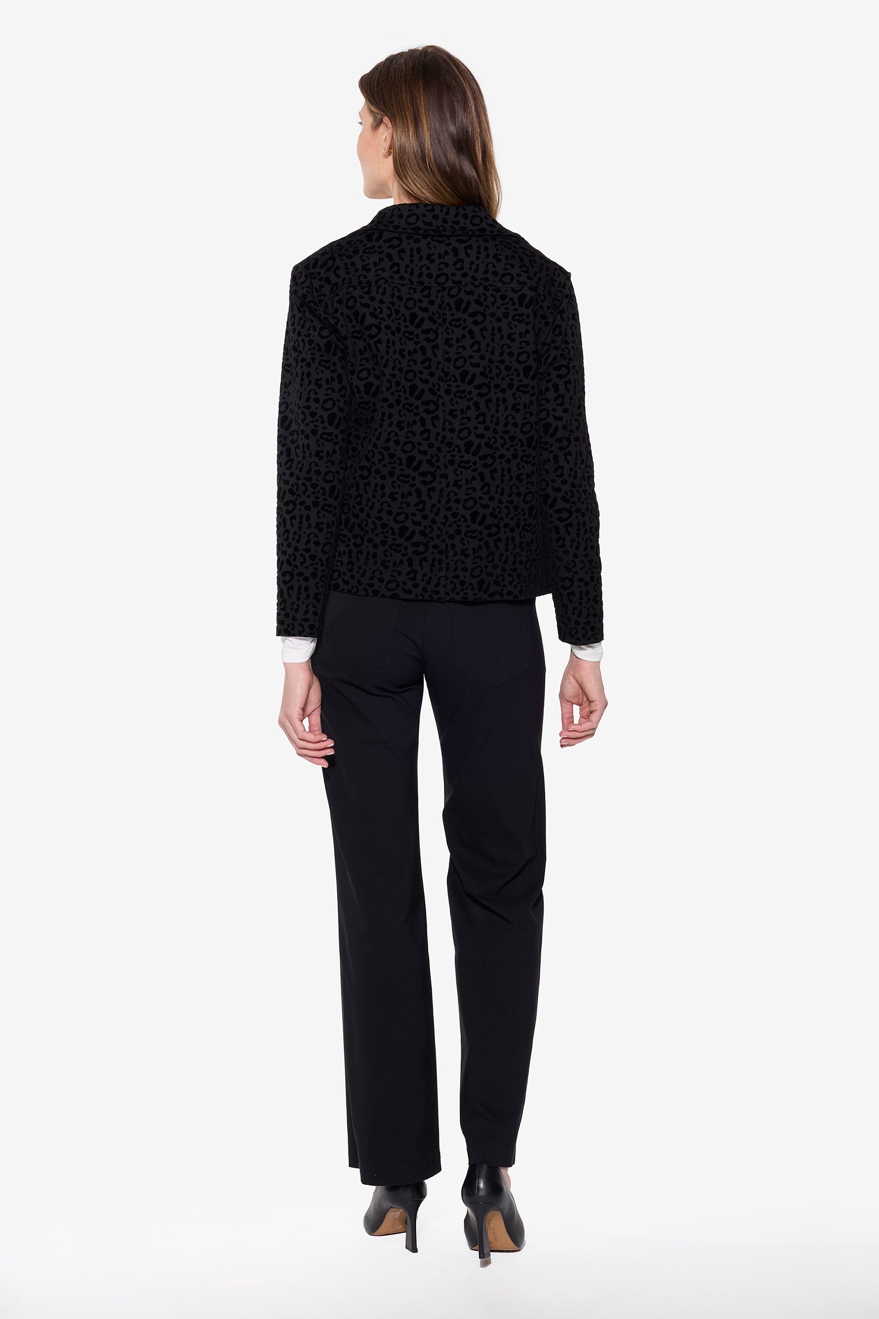 Person wearing a black textured shirt jacket and black pants on a white background