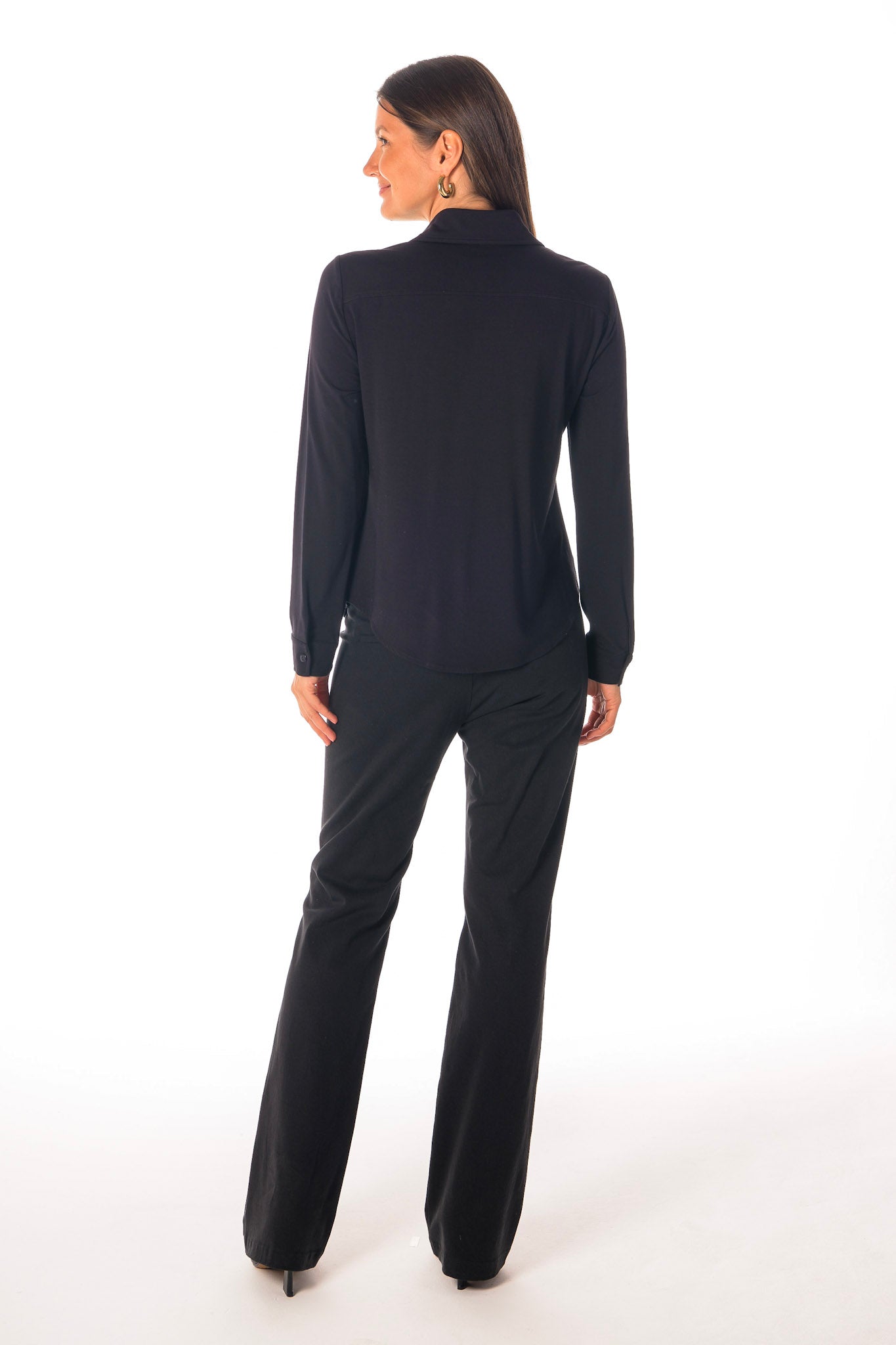 Person wearing a black long-sleeve top and pants on a white background back View