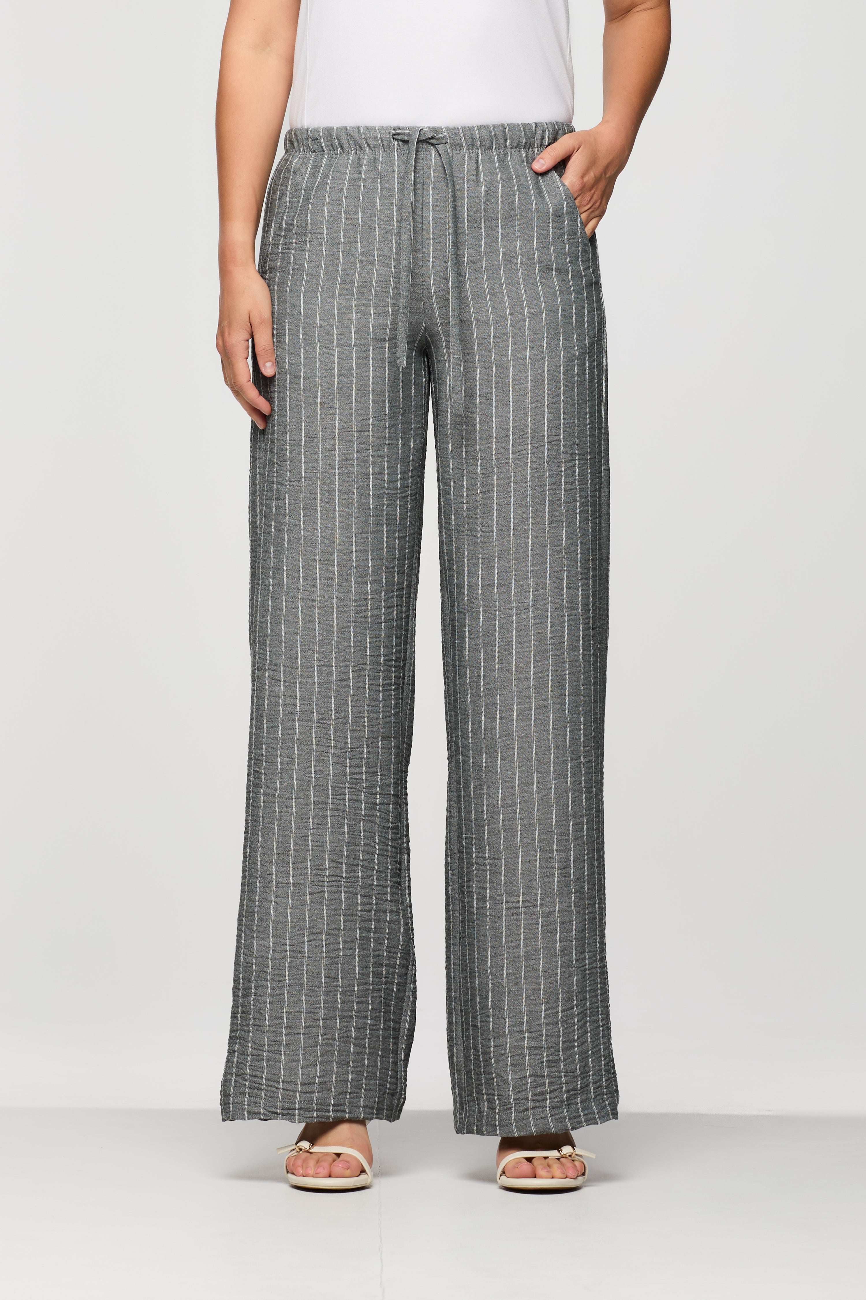 Woman wearing grey pinstripe wide leg pants with a drawstring elastic waistband and relaxed fit, shown from the front.