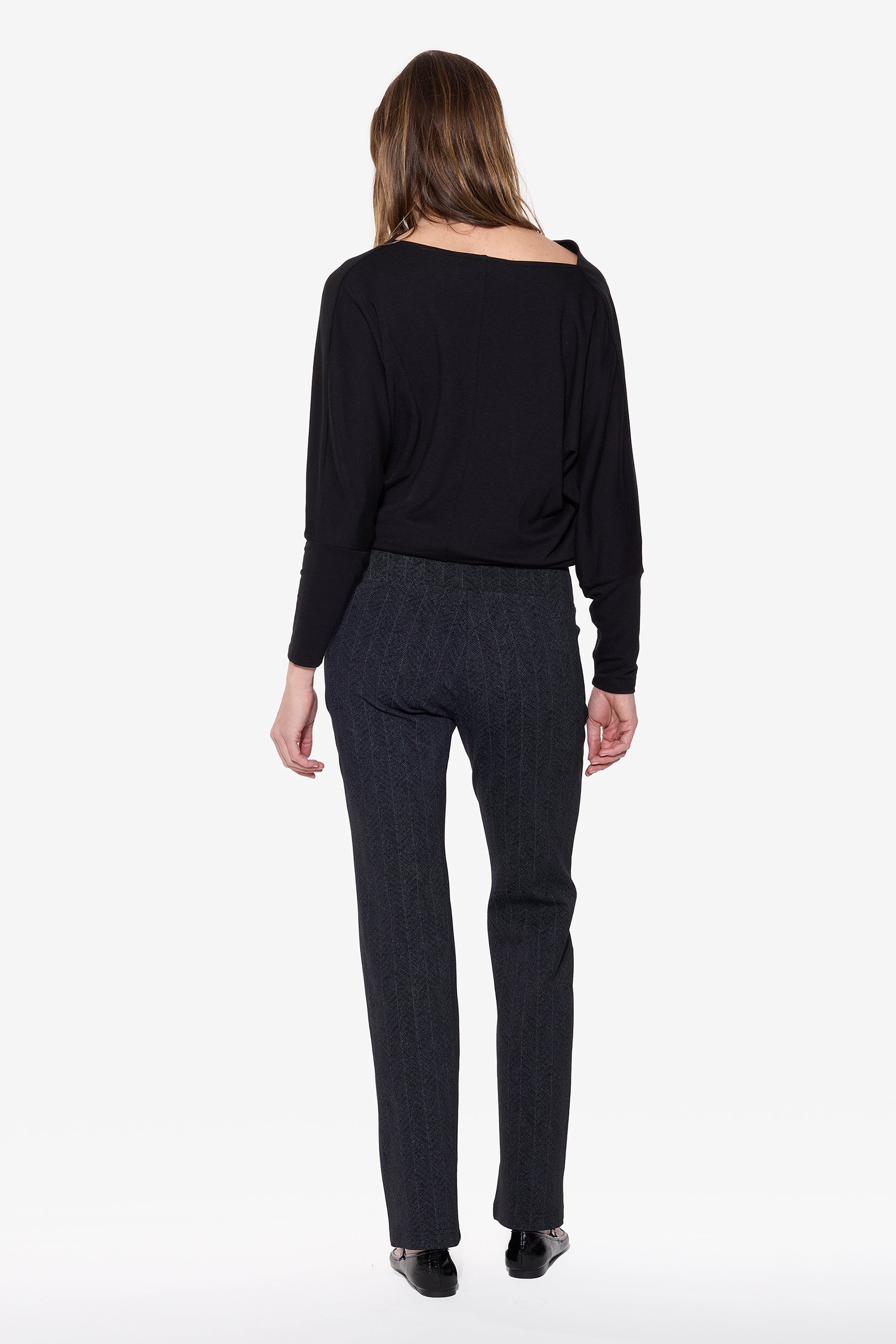 Woman wearing a black top and gray pants on a white background