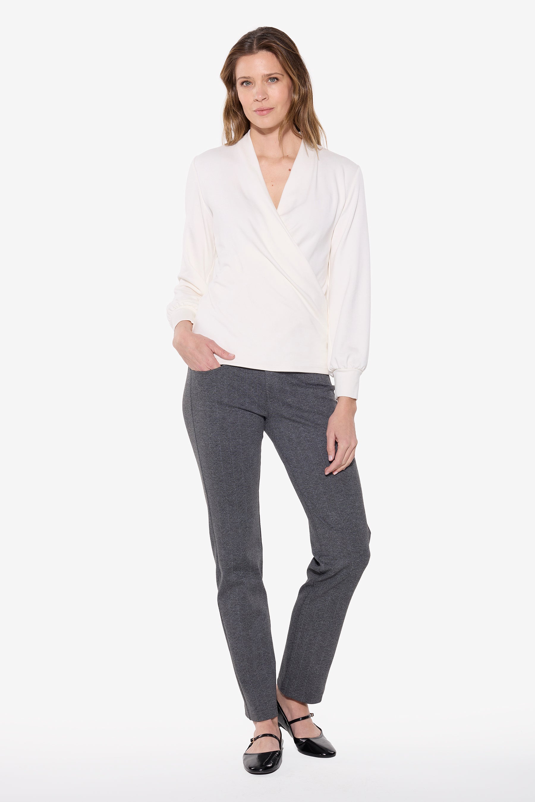 Woman wearing a white wrap top and gry chevron pants on a white background