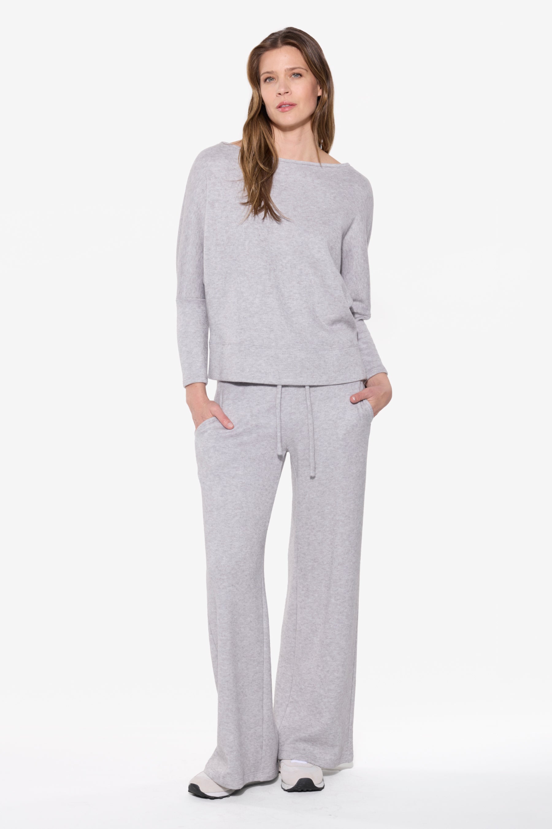 Woman wearing a gray sweater and pants on a white background