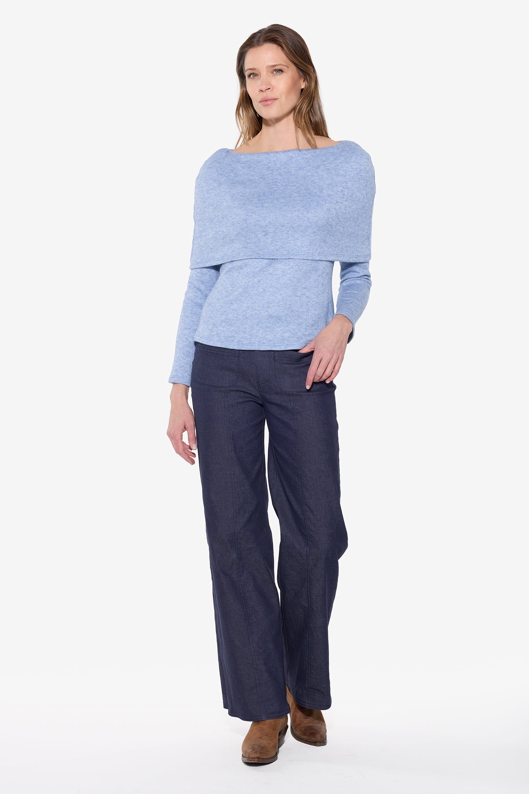 Woman wearing a light blue off-shoulder top and dark blue pants on a white background