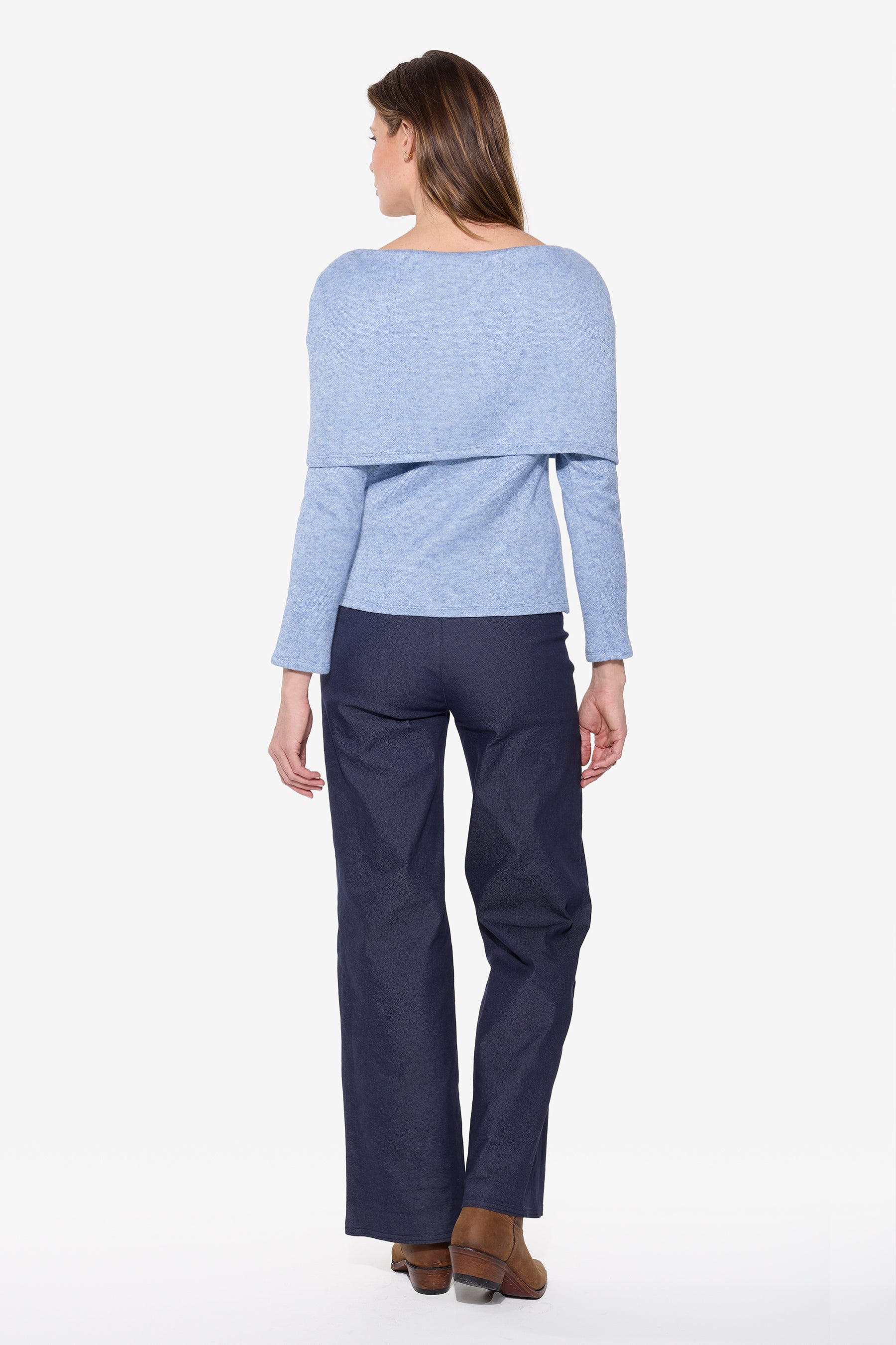 Woman wearing a light blue sweater and dark blue pants on a white background