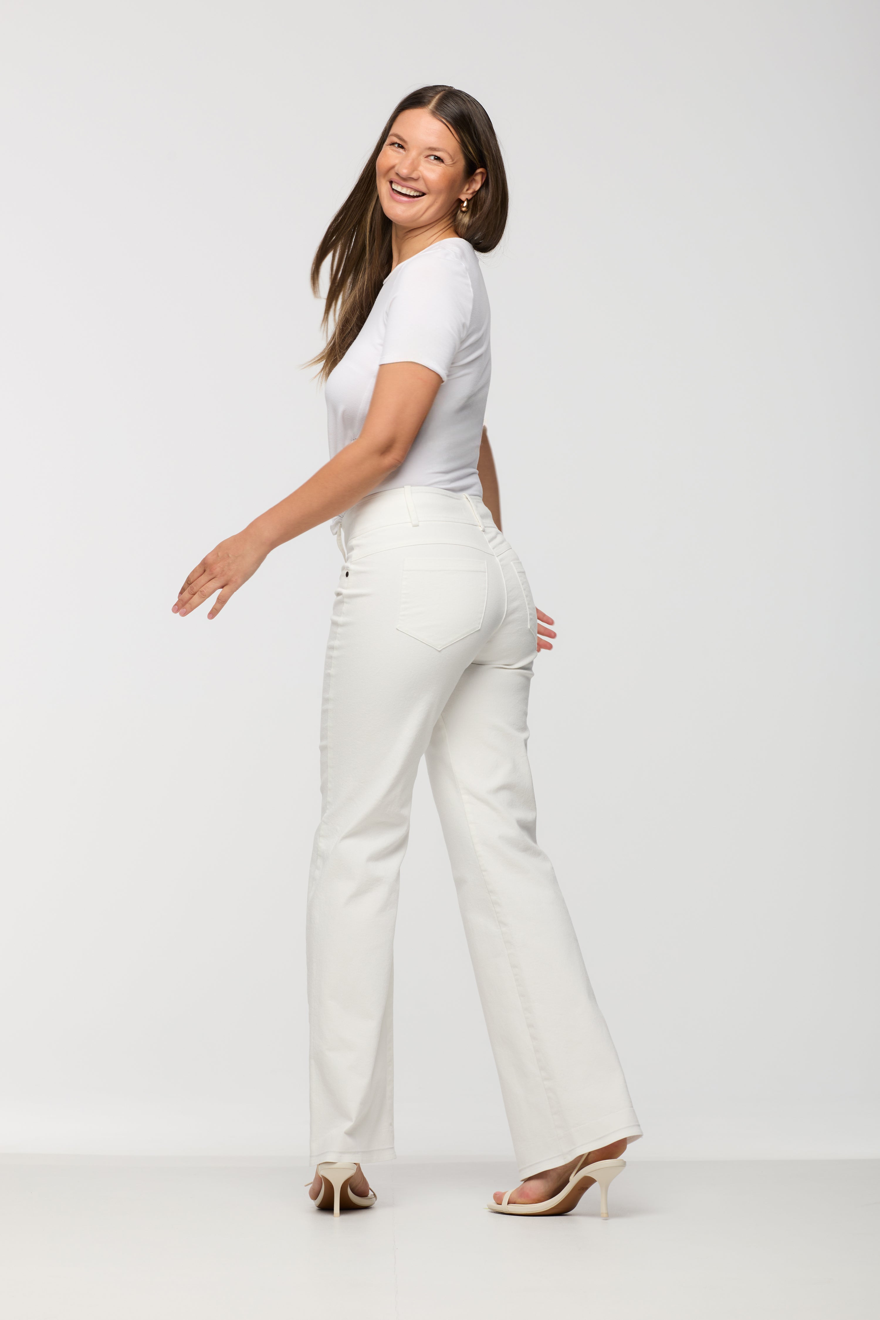 Woman wearing a white t-shirt and white pants on a plain background