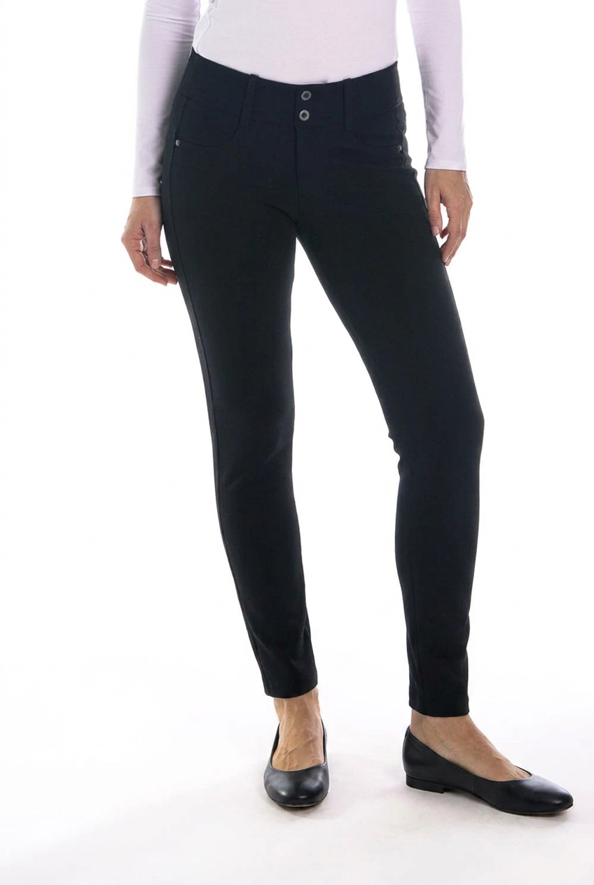 Black slim-fit ankle-length pants shown on a model from the waist down, paired with a white long-sleeve top and black flats against a white studio background.