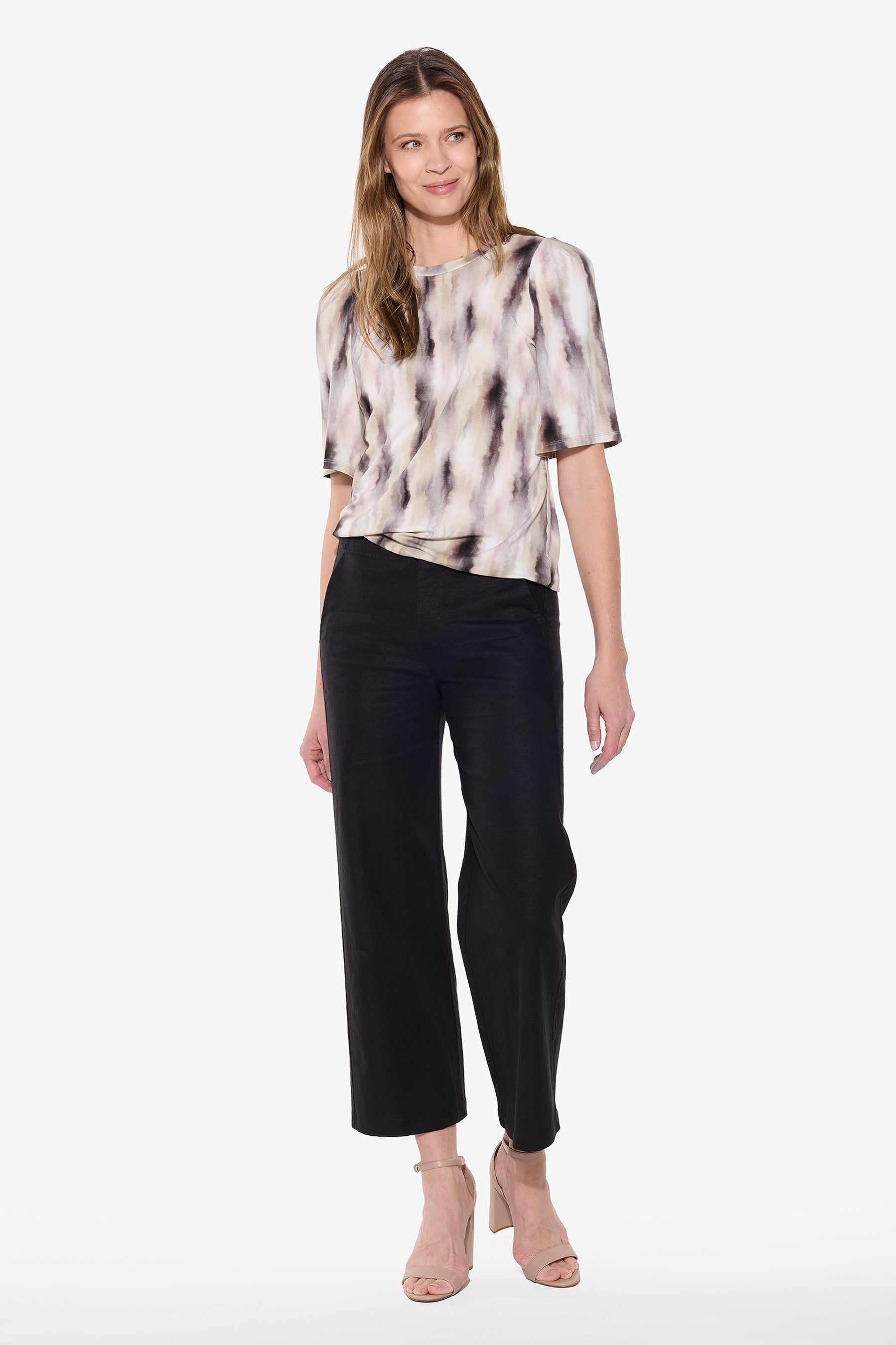 Woman wearing a tie-dye top and black pants on a white background