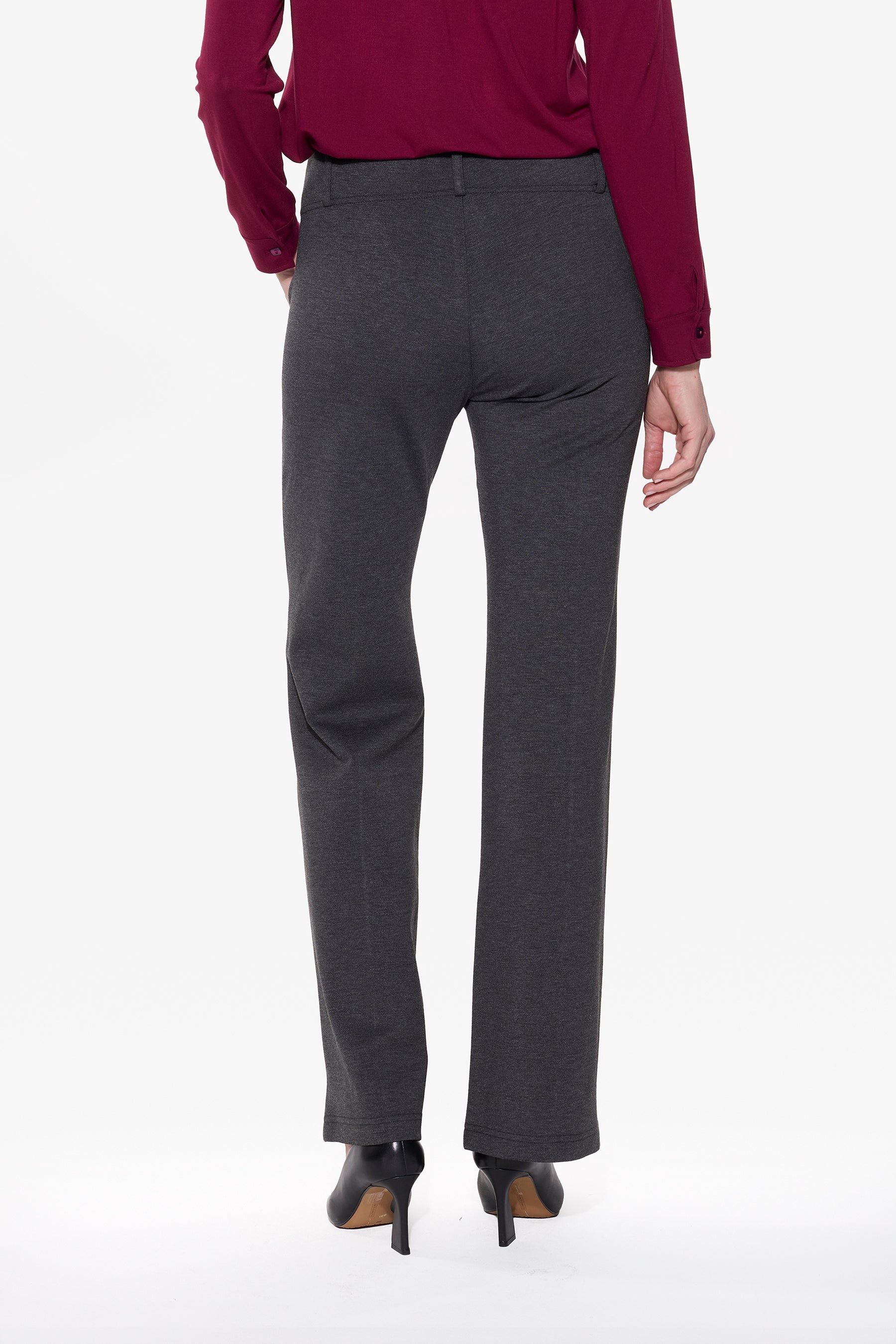 Person wearing charcoal pants and a red top on a white background back view