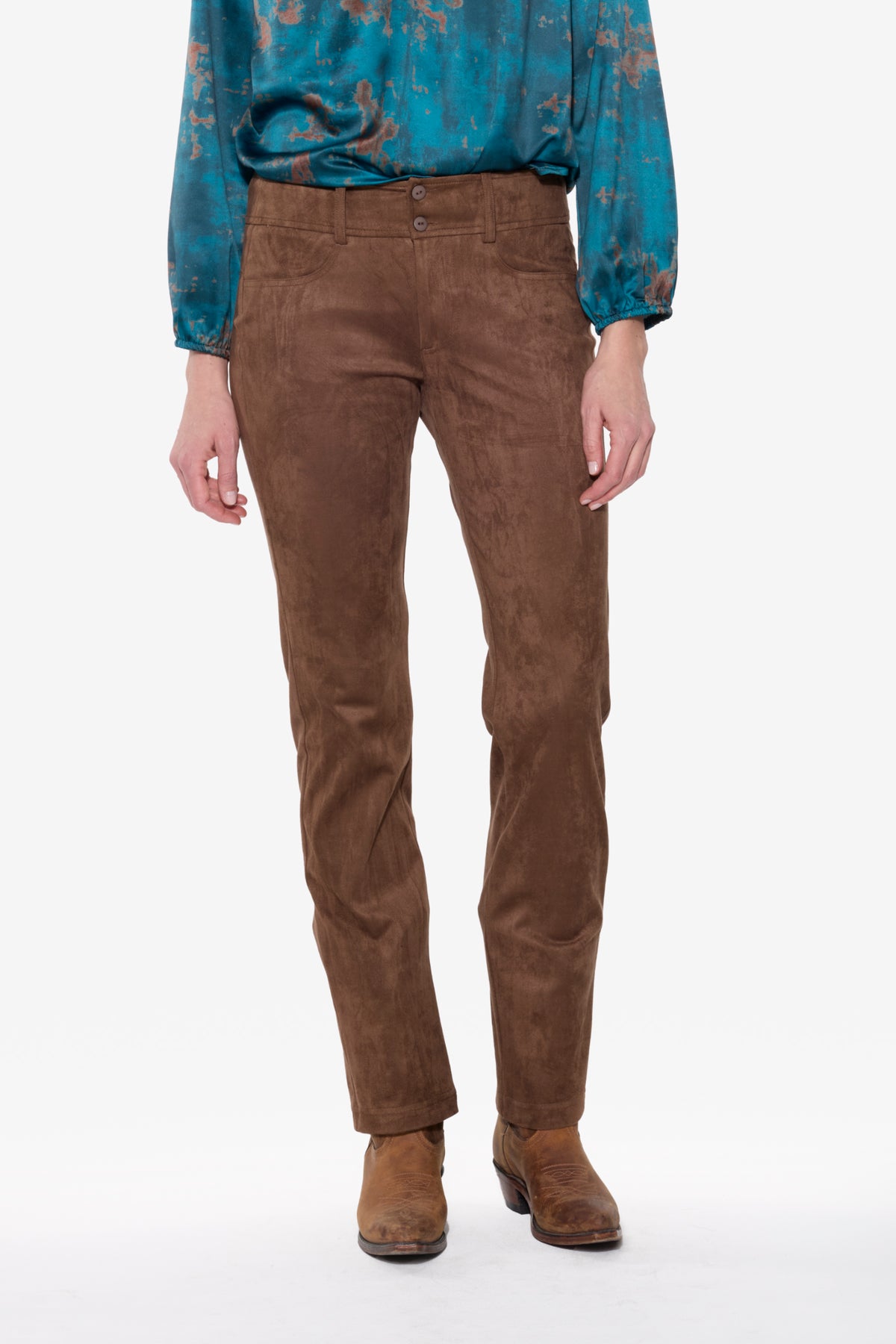 Person wearing brown stretch suede pants and a blue patterned shirt on a white background